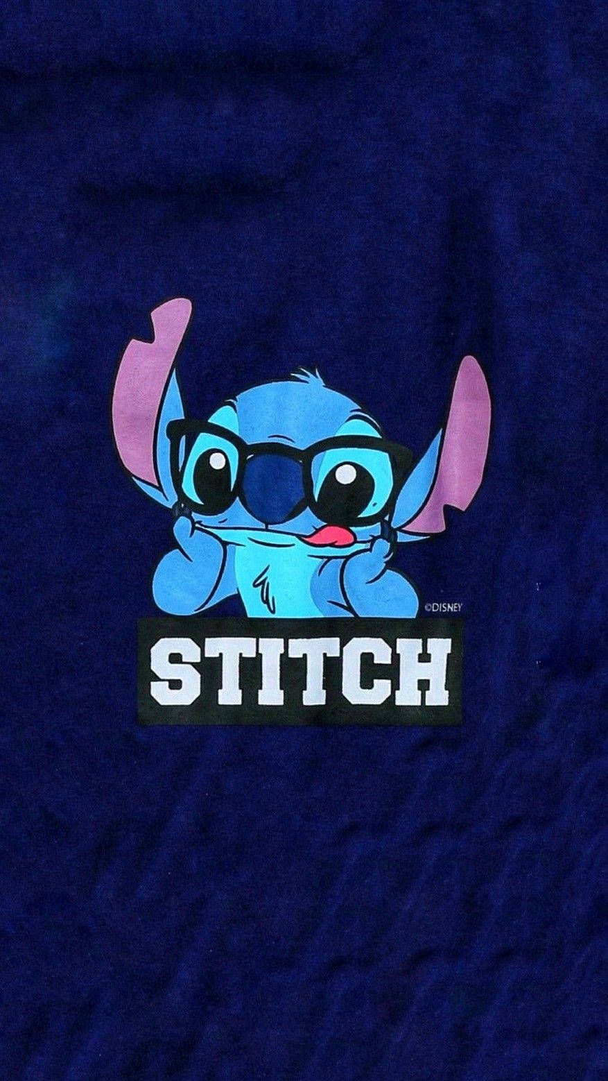 Stitch 桌布 壁紙 — 一個藍色卡通外星人，有粉紅色耳朵和眼鏡，從深藍色布料背景中探出頭來，下方有「STITCH」文字。