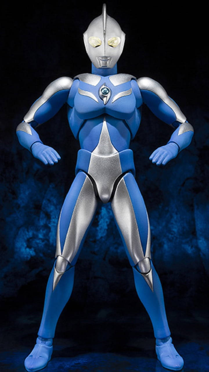 Ultraman 桌布 壁紙 — 一個藍色和銀色的超人力霸王動作人偶，在深藍色紋理背景前自信地站立，眼睛發光。