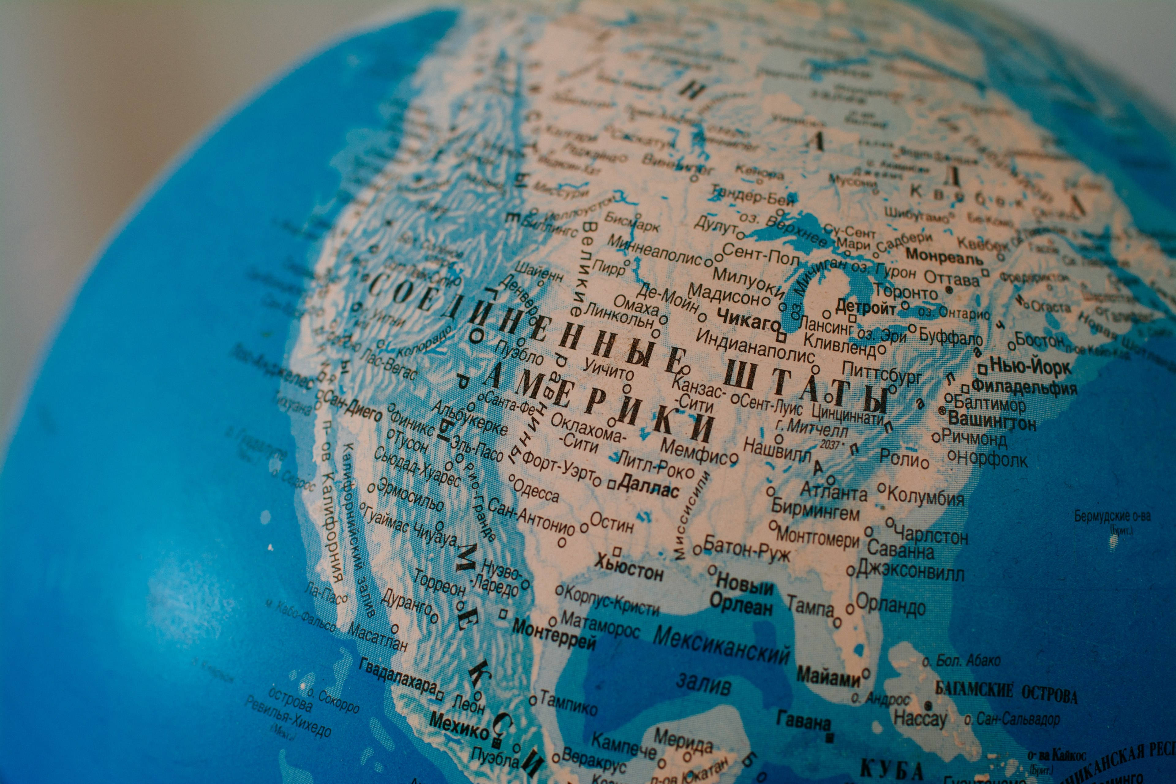 United States Map 桌布 壁紙 — 一個藍色地球儀的特寫，突出顯示美國，並附有俄語和英語的城市名稱。