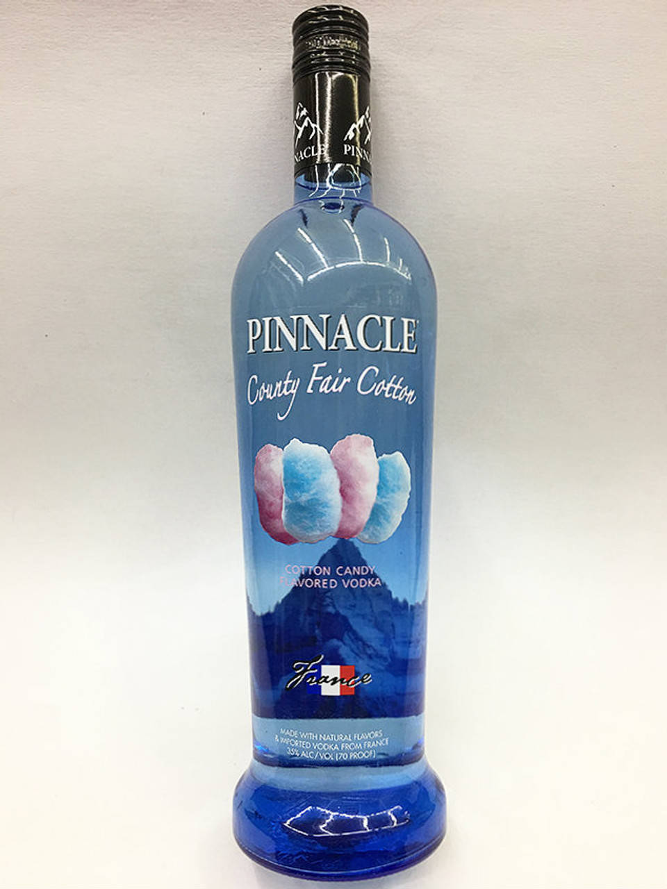 bottle 桌布 壁紙 — 一個藍色的 Pinnacle County Fair Cotton 伏特加酒瓶，帶有棉花糖圖案，立在純白色背景前。