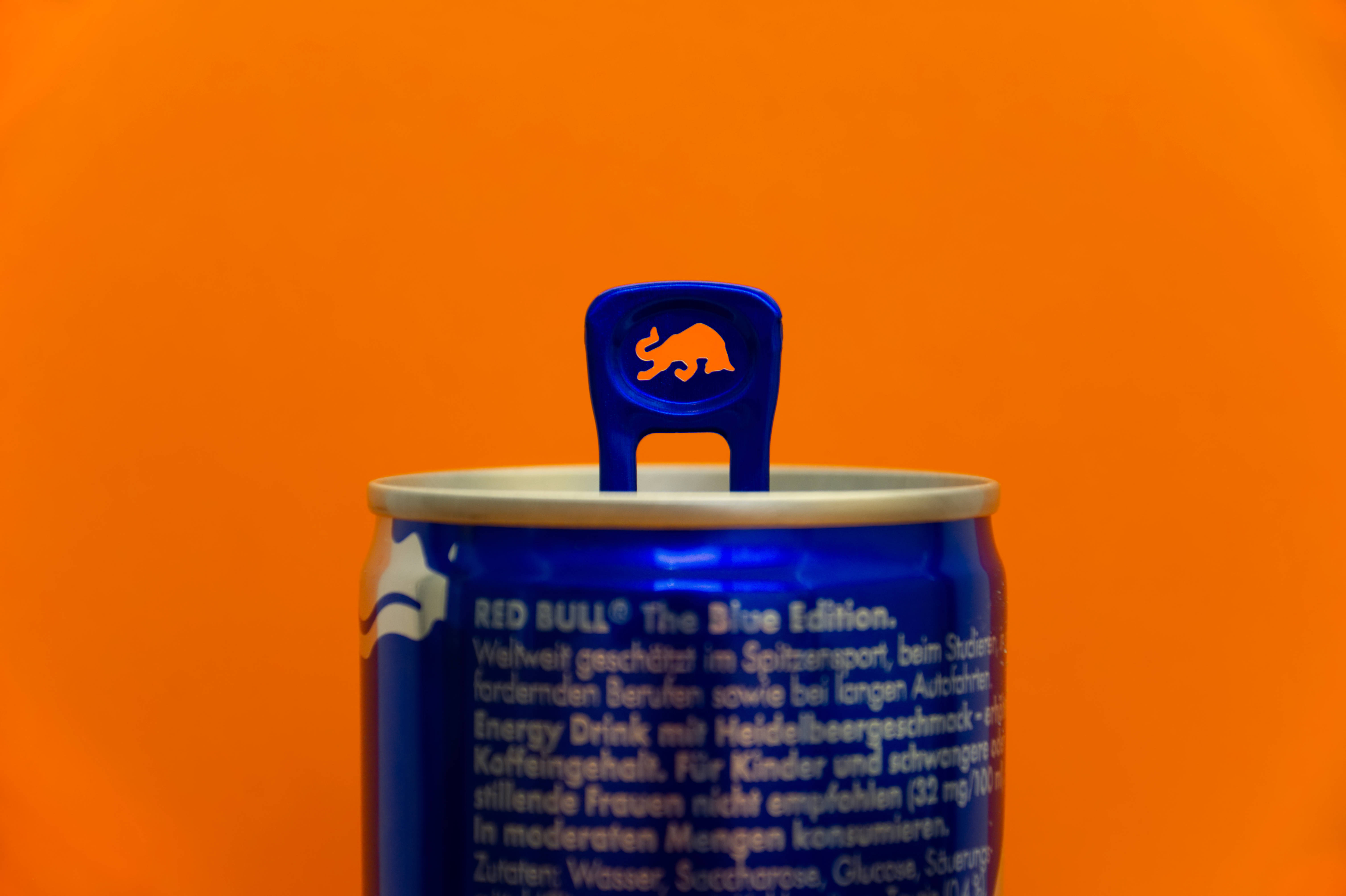 you can do it 桌布 壁紙 — 一個藍色的Red Bull罐，上面有橙色公牛標誌的拉環，站在充滿活力的橙色背景前。