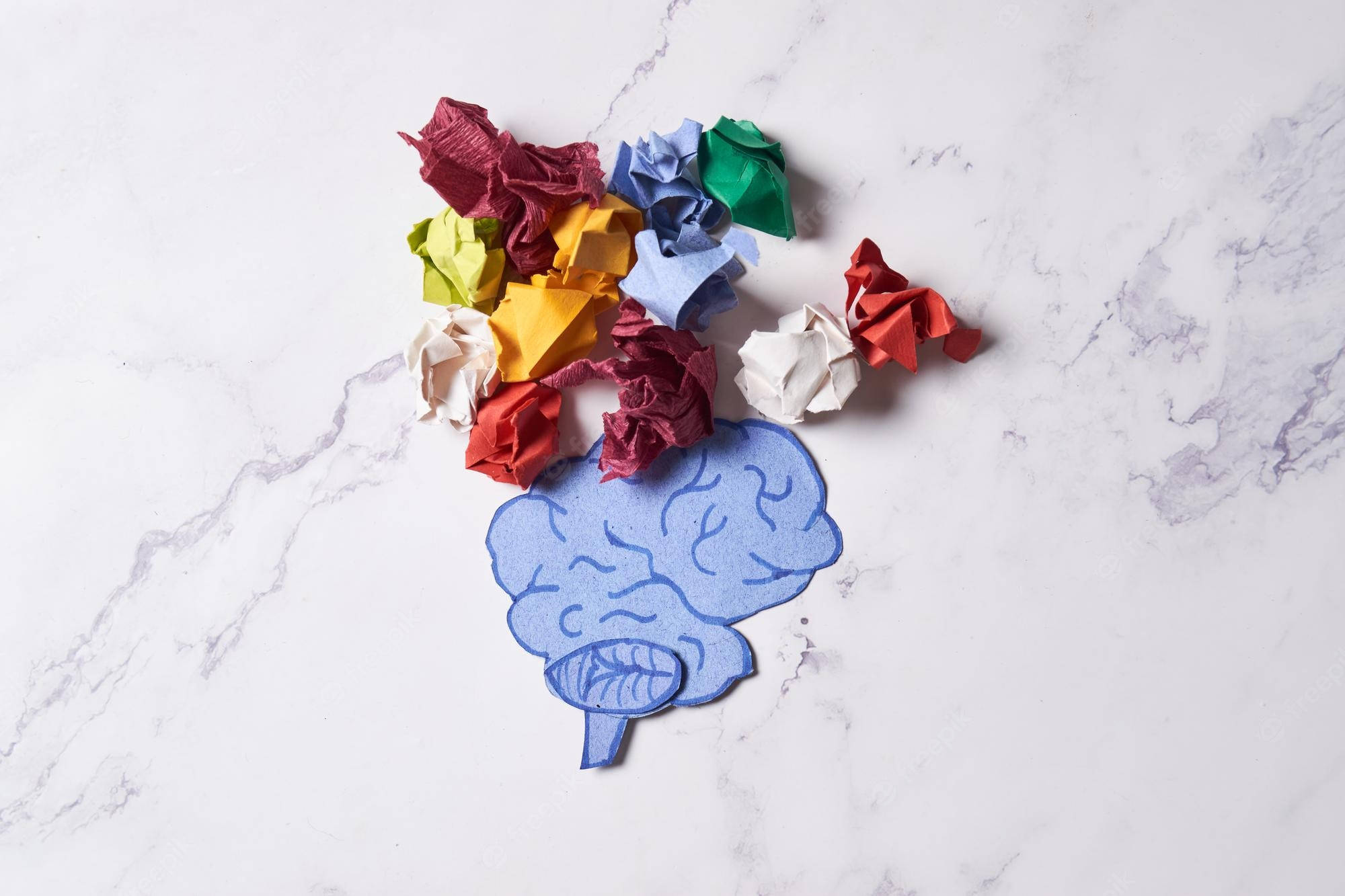 Brain 桌布 壁紙 — 一個藍色紙質大腦剪紙，周圍散落著彩色皺紙球，放在白色大理石表面上。
