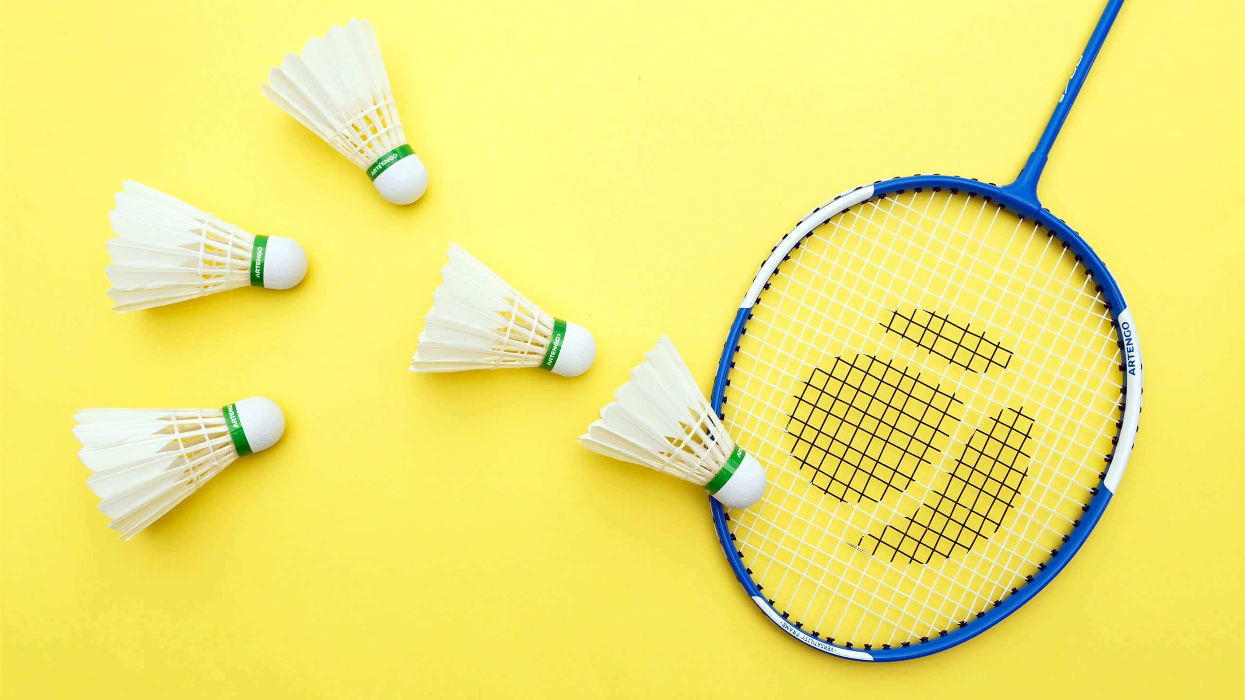 HD Badminton 桌布 壁紙 — 一個藍色羽毛球拍和五個白色羽毛球排列在明亮的黃色背景上。