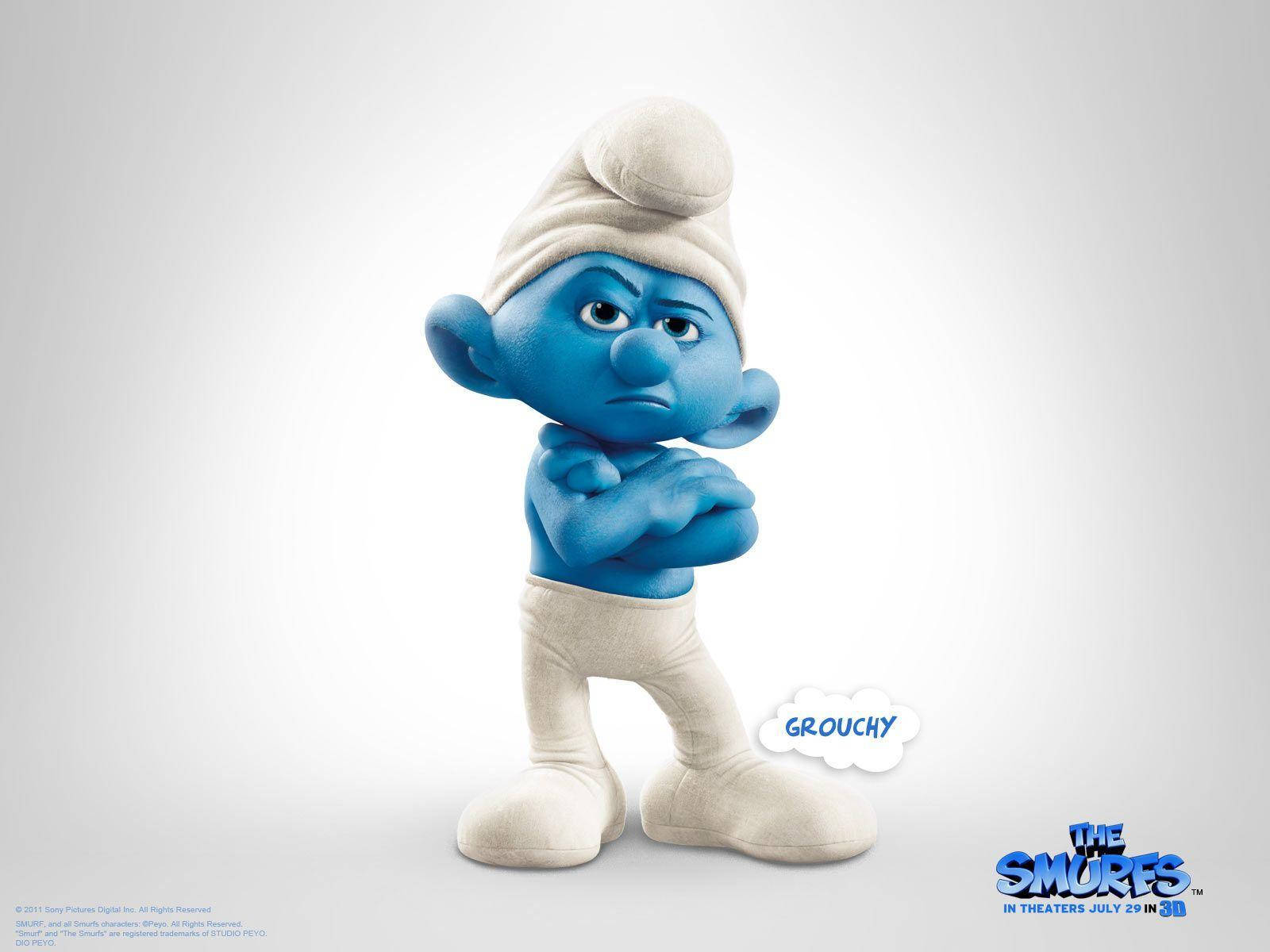 Smurfs 桌布 壁紙 — 一個藍色藍精靈交叉雙臂，面露不悅表情，站在純白色背景前。