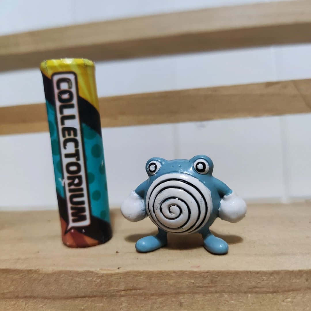 寶可夢 桌布 壁紙 — 一個藍色螺旋圖案青蛙公仔站在木質表面上一個色彩繽紛的「COLLECTORIUM」管旁邊。
