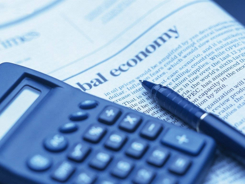 計算機 桌布 壁紙 — 一個藍色計算機和一支筆放在一篇關於全球經濟的報紙文章上，處於冷色調單色燈光下。