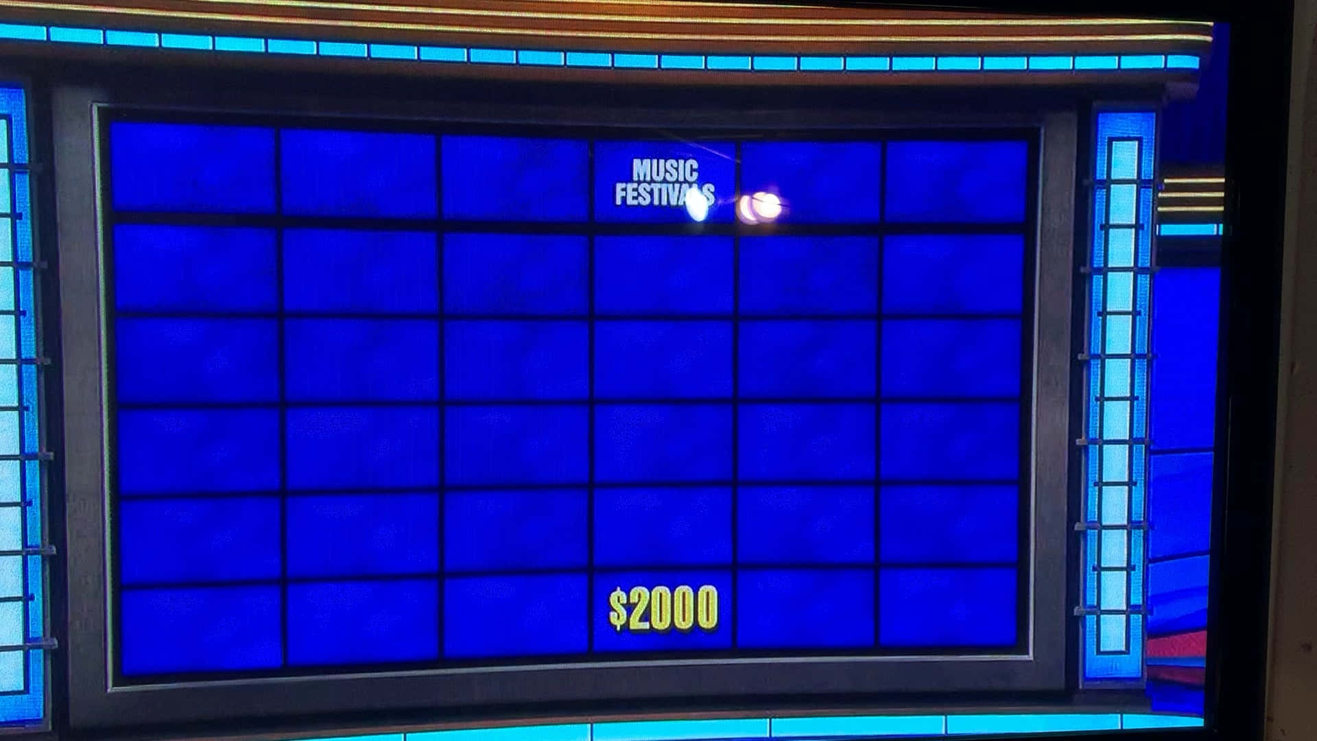 jeopardy 桌布 壁紙 — 一個藍色遊戲節目螢幕，以亮黃色文字顯示「MUSIC FESTIVALS」和「$2000」。