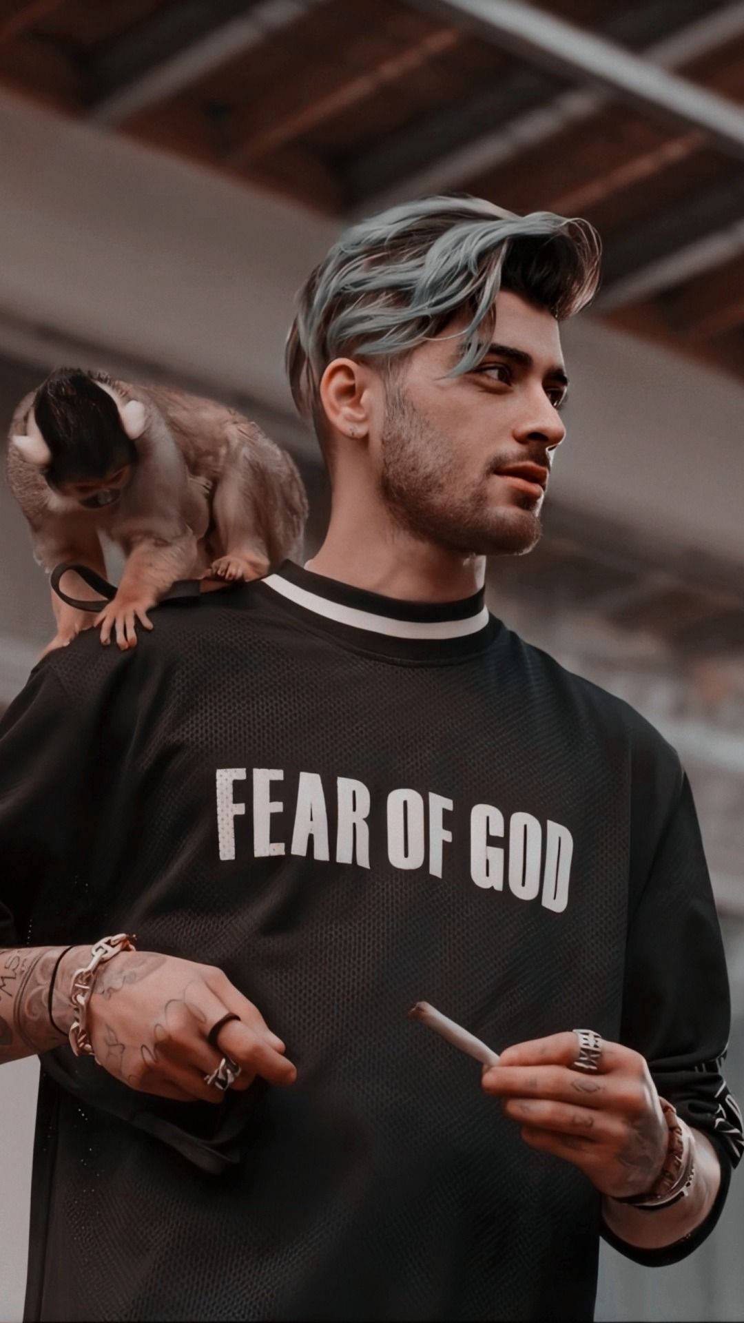One Direction 桌布 壁紙 — 一個藍色頭髮的男人肩上有一隻猴子，穿著 'Fear of God' 襯衫，在工業環境中拿著香煙。