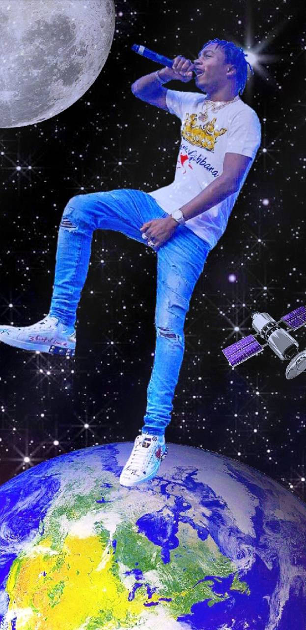 Lil Tjay 桌布 壁紙 — 一個藍色頭髮的饒舌歌手在發光的地球上饒舌，在一個巨大的月亮下，周圍有星星和衛星。