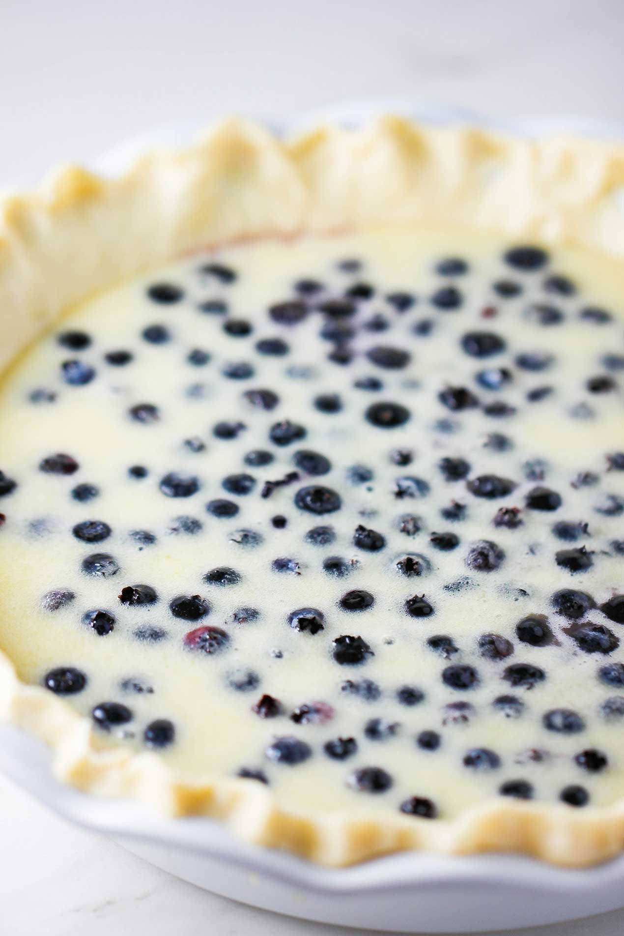 Pie 桌布 壁紙 — 一個藍莓派的特寫，內有奶油卡士達餡料，金色波浪狀派皮，放在白色盤子上。