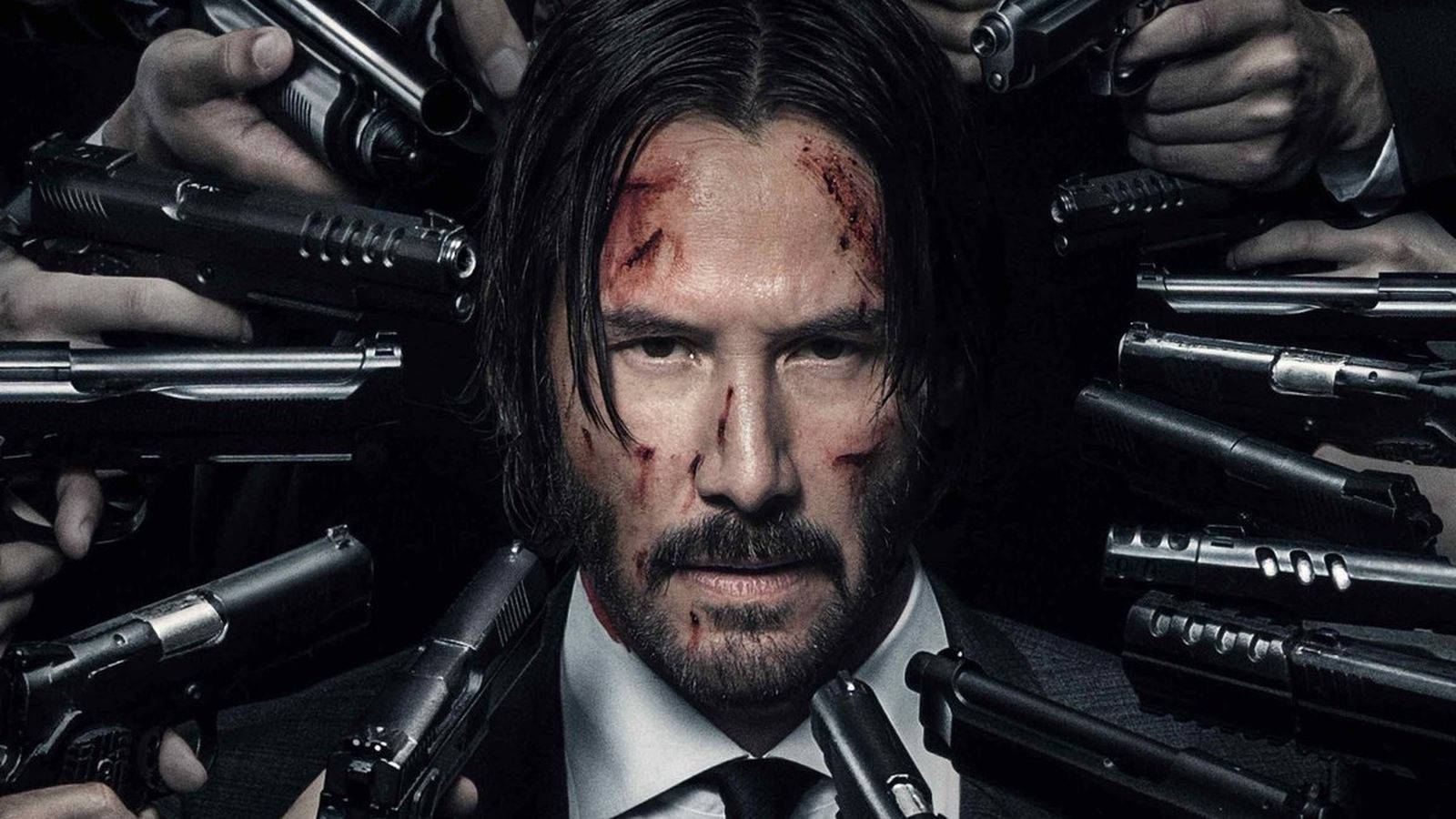 John Wick 桌布 壁紙 — 一個血跡斑斑、身穿西裝的男人在黑暗的電影場景中，被多隻持槍的手包圍，眼神銳利。