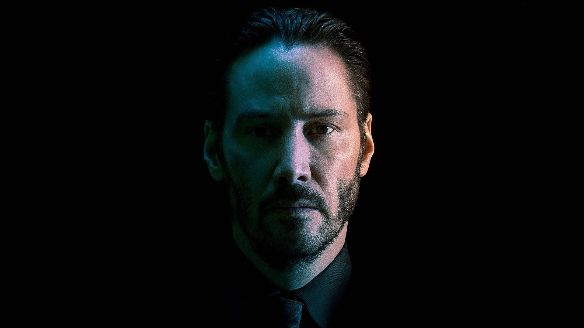 John Wick 桌布 壁紙 — 一個表情嚴肅的男人被冷藍光照亮，背景為黑色。