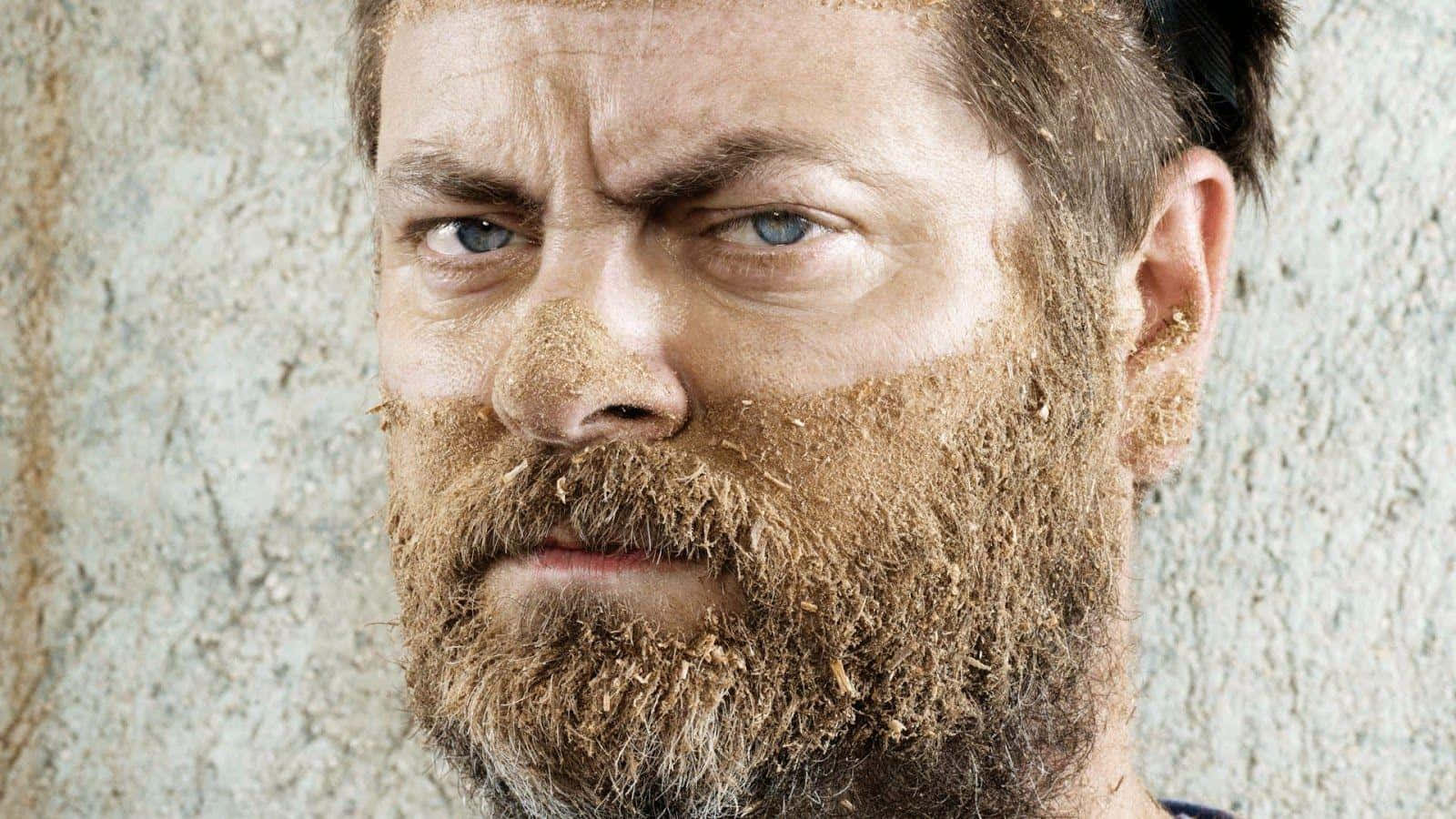 nick offerman 桌布 壁紙 — 一個表情暴躁的男人，鬍子裡嵌著泥土和草，背景是粗糙有紋理的牆壁。