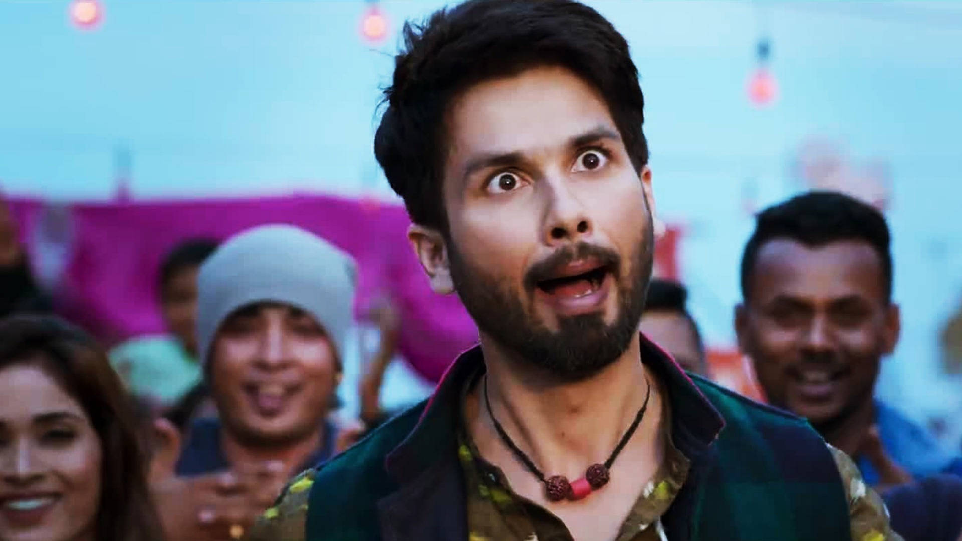 Shahid Kapoor 桌布 壁紙 — 一個表情震驚的男人向上凝視，周圍是微笑的人們在節日聚會中。