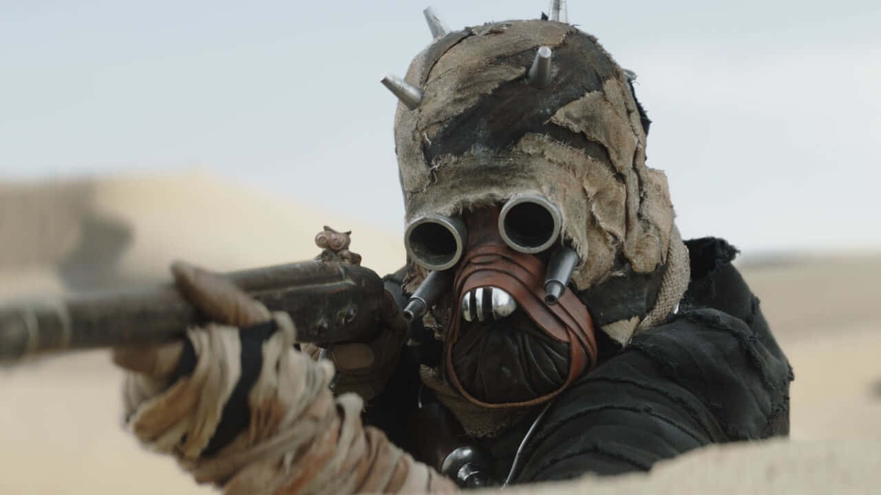 Tusken Raiders 桌布 壁紙 — 一個被沙覆蓋的戰士，戴著尖刺頭盔，在朦朧的天空下從沙漠戰壕中瞄準爆能步槍。