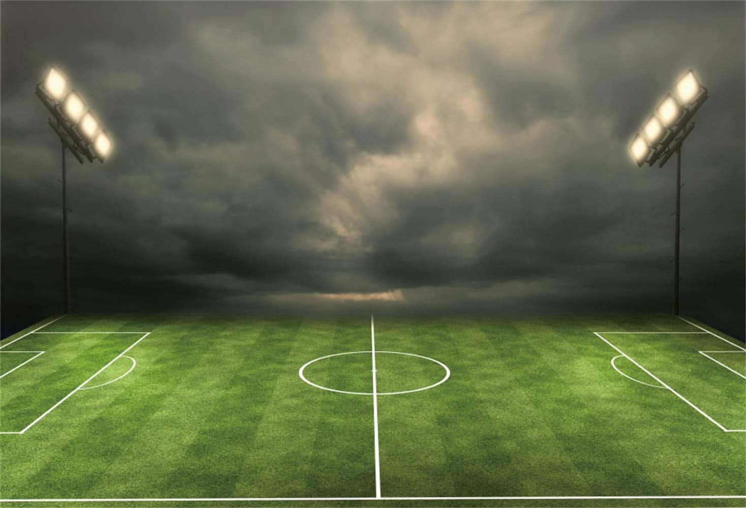 Football Field 桌布 壁紙 — 一個被雨水浸透的足球場，在暴風雨的天空下，被高聳的體育場燈光照亮，投射出戲劇性的陰影。