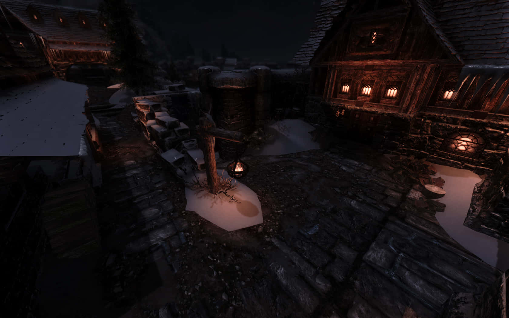 Skyrim Windhelm 桌布 壁紙 — 一個被雪覆蓋的中世紀村莊夜景，木屋中透出溫暖的燈籠光芒，中央的營火照亮了積雪。