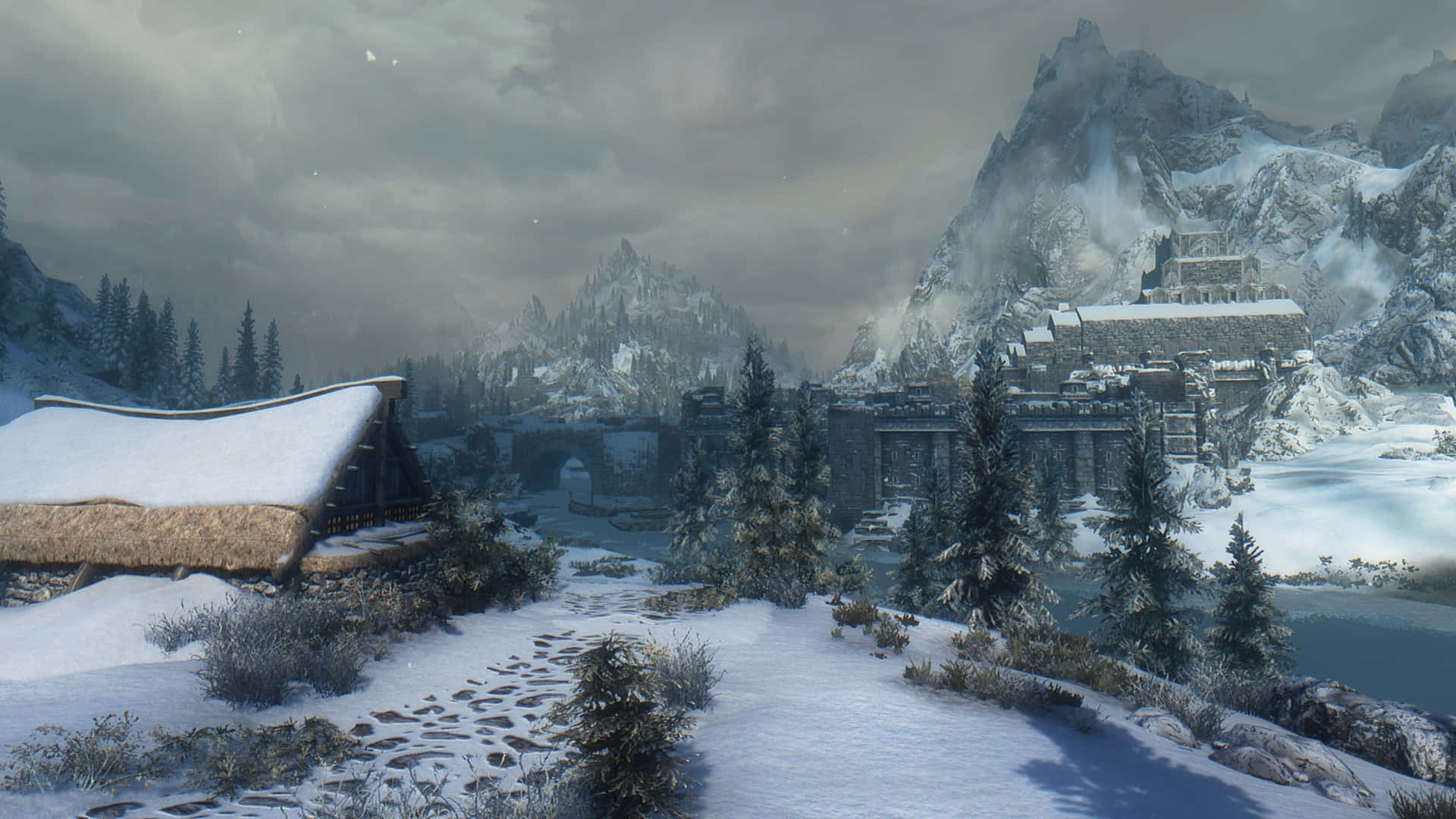Skyrim Windhelm 桌布 壁紙 — 一個被雪覆蓋的山村，有石頭建築和松樹，在陰沉的冬日天空下。