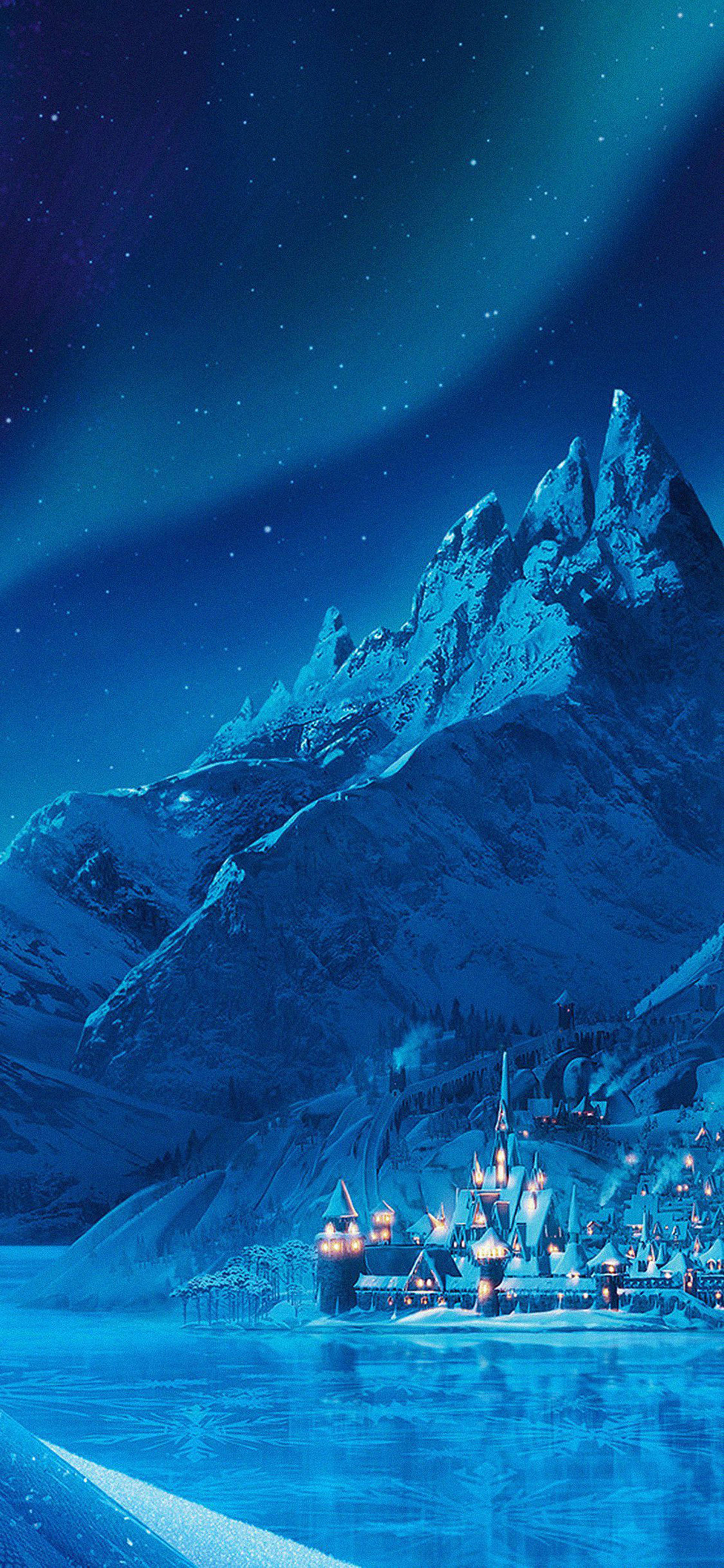 冰雪城堡 桌布 壁紙 — 一個被雪覆蓋的山村在繁星點點的夜空下溫暖地發光，北極光在上方舞動。