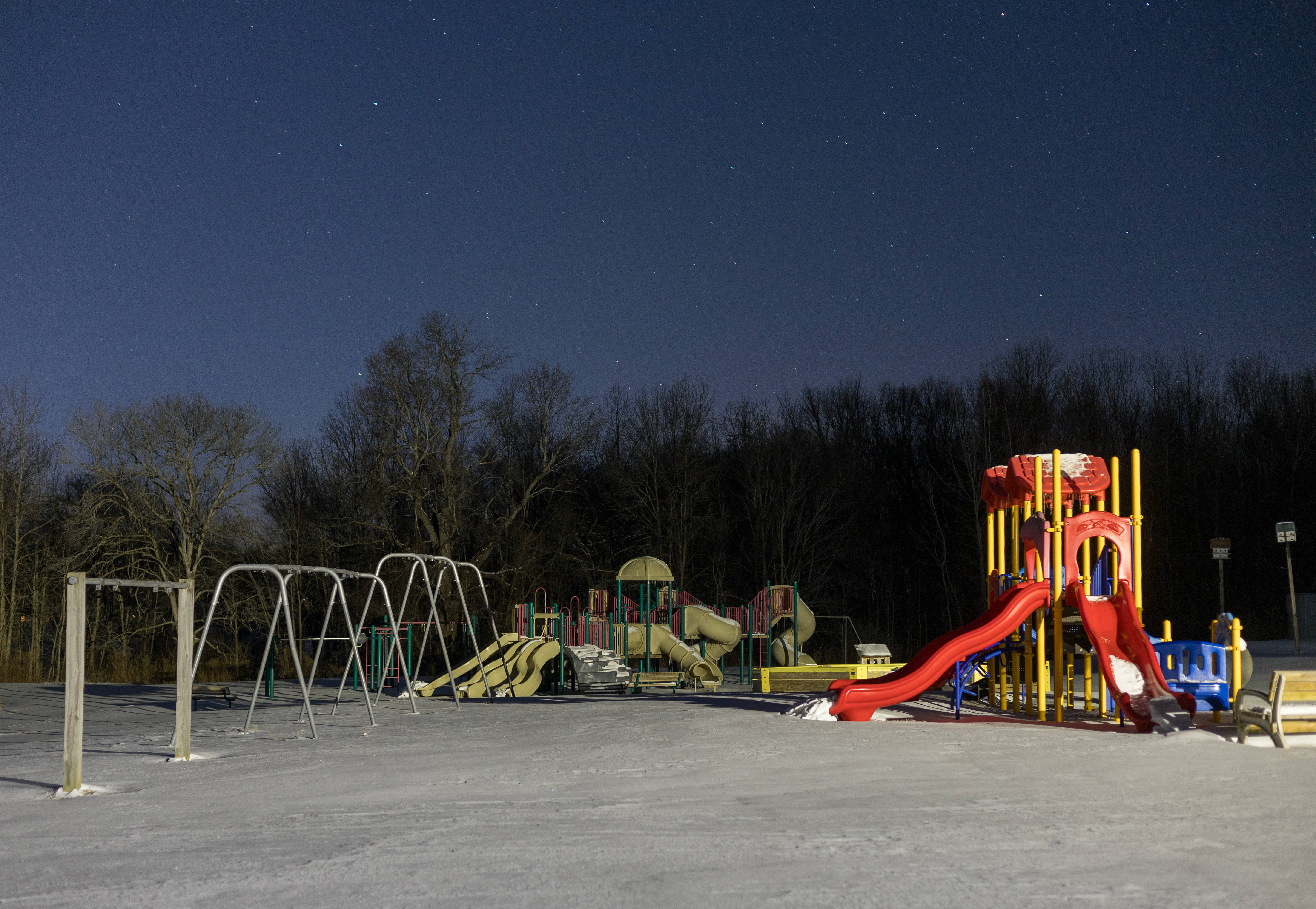 Playground 桌布 壁紙 — 一個被雪覆蓋的遊樂場，背景是星空和光禿禿的樹木。