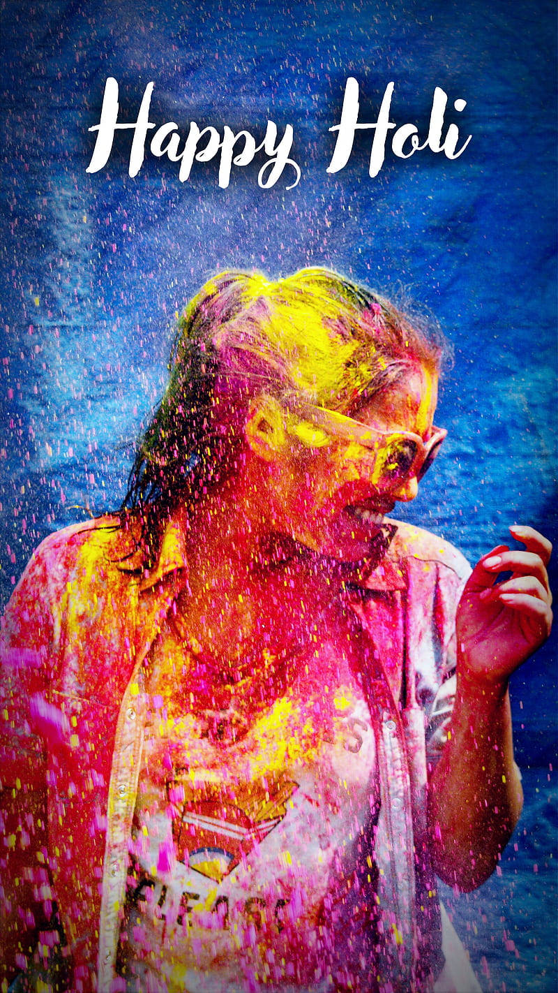 Holi 桌布 壁紙 — 一個被鮮豔的Holi顏色覆蓋的快樂人物在深藍色背景前，粉末在他們周圍爆炸時微笑。