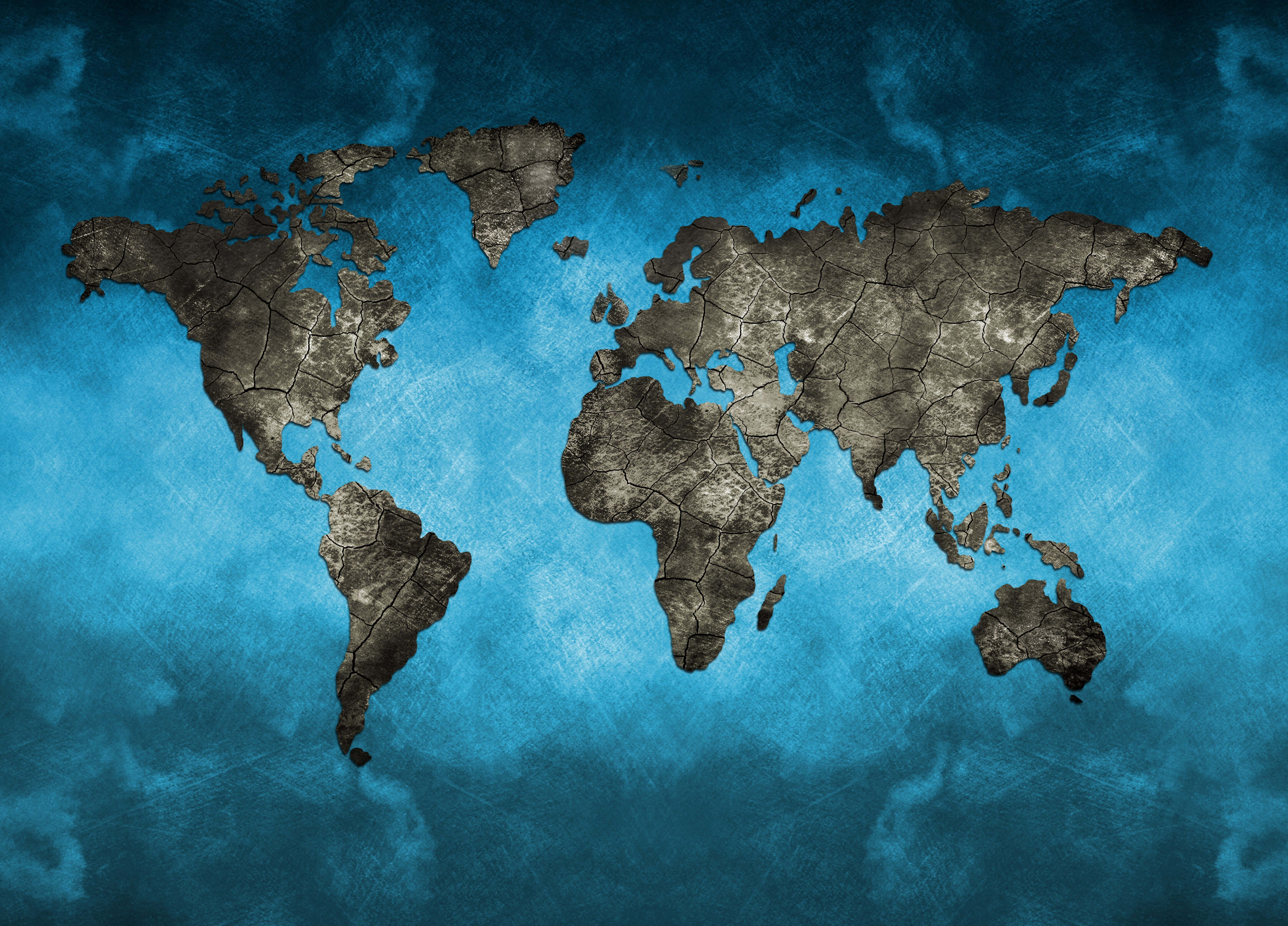 World Map Aesthetic 桌布 壁紙 — 一個裂開的地球世界地圖以深灰色漂浮在帶紋理的青藍色背景上。
