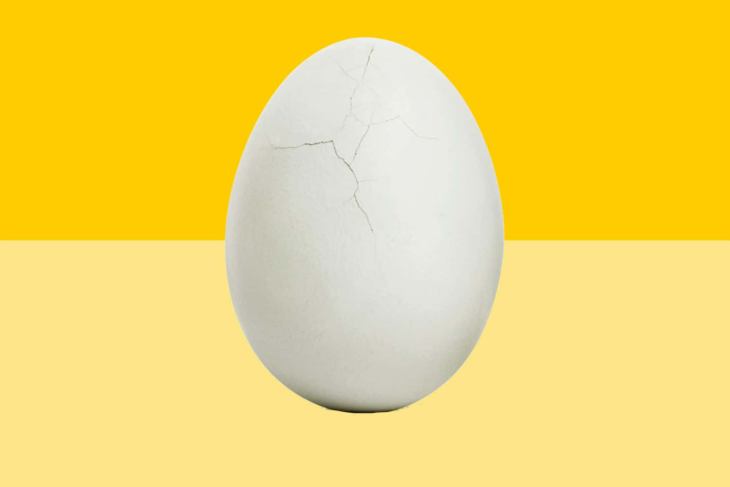 Egg 桌布 壁紙 — 一個裂開的白雞蛋，居中於大膽的黃色和淡黃色背景上。