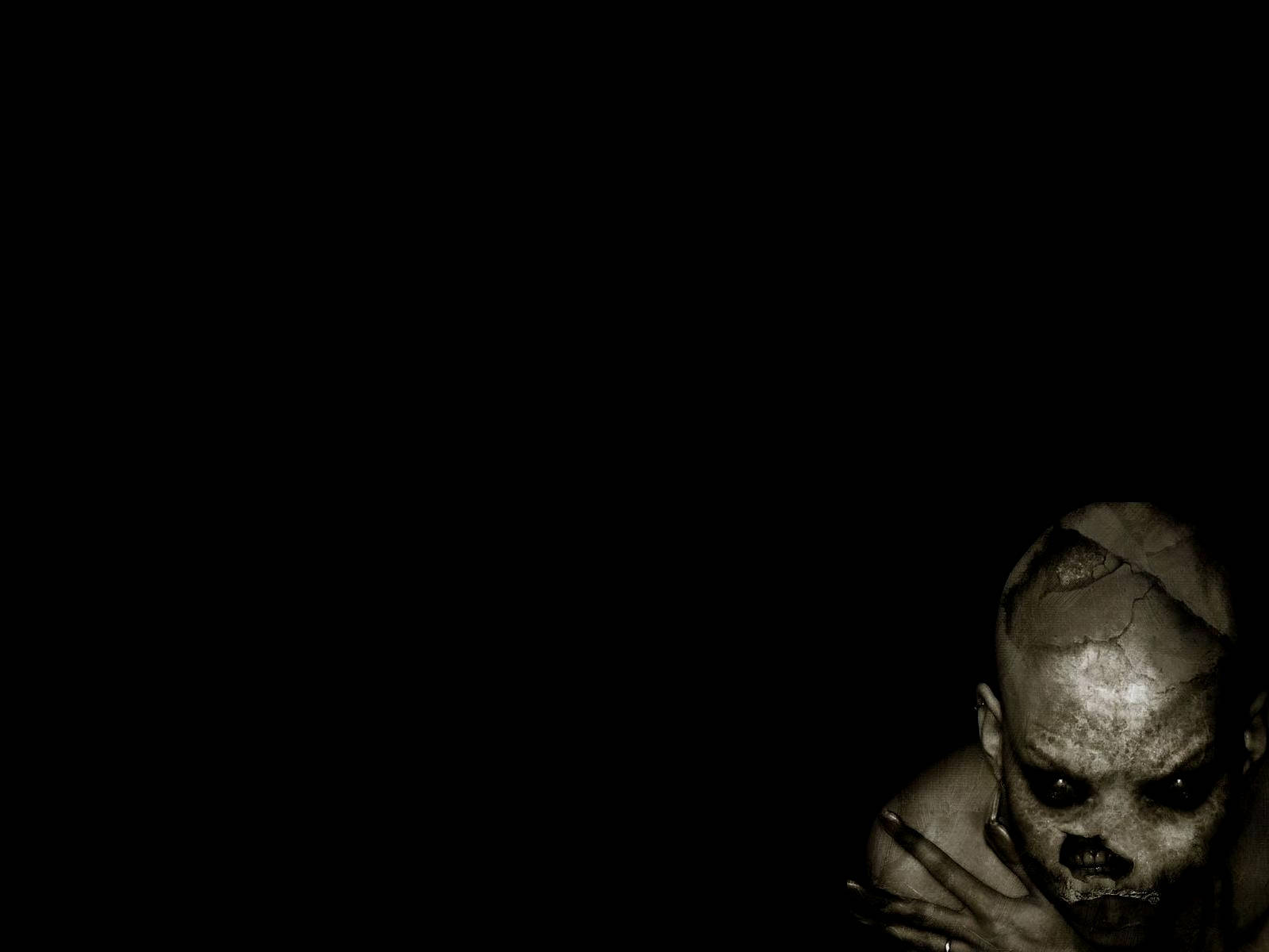 Spooky Season 桌布 壁紙 — 一個裂開的骷髏臉人物從黑暗中出現，在鮮明的黑白恐怖場景中。