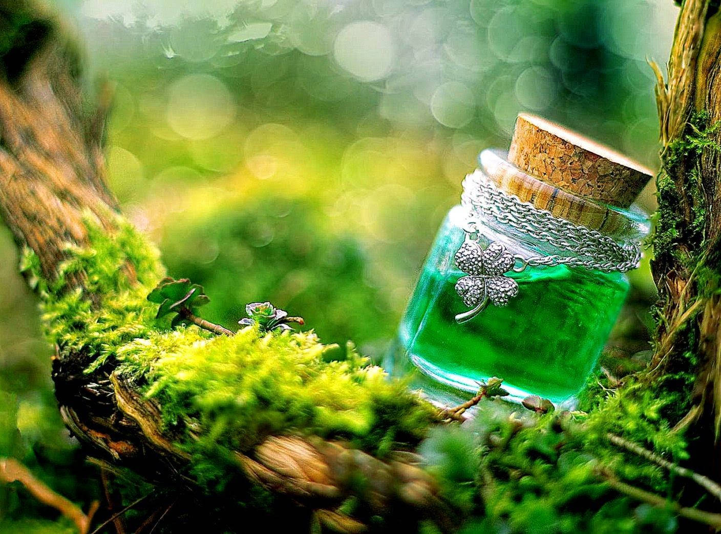 lucky 桌布 壁紙 — 一個裝滿發光綠色液體和四葉草飾物的玻璃瓶，擱在陽光普照的森林中長滿苔蘚的樹枝上。