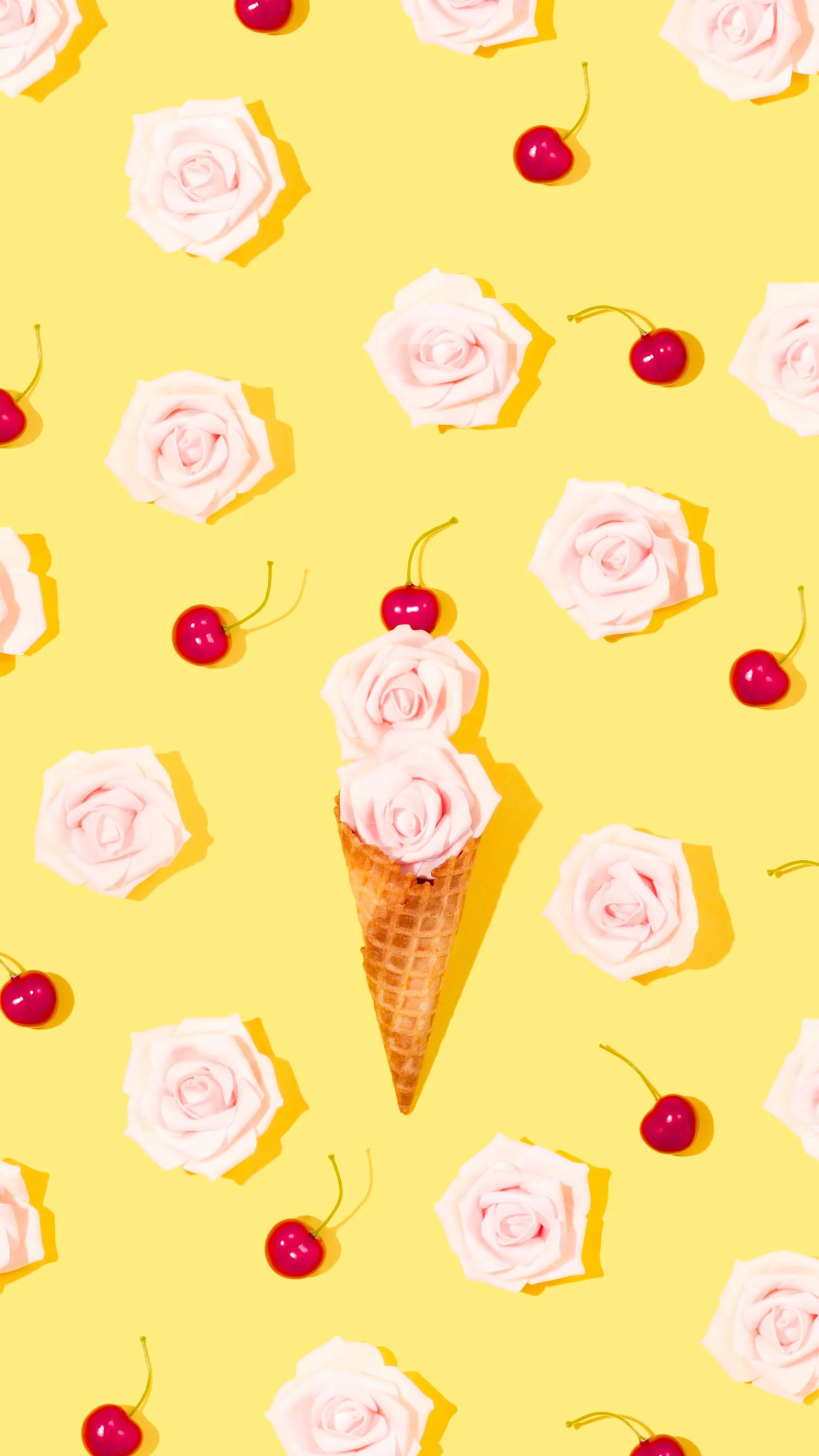 Spring iPhone 桌布 壁紙 — 一個裝滿粉紅玫瑰並以櫻桃點綴的鬆餅筒，在散落著玫瑰和櫻桃的鮮黃色背景中央展示。