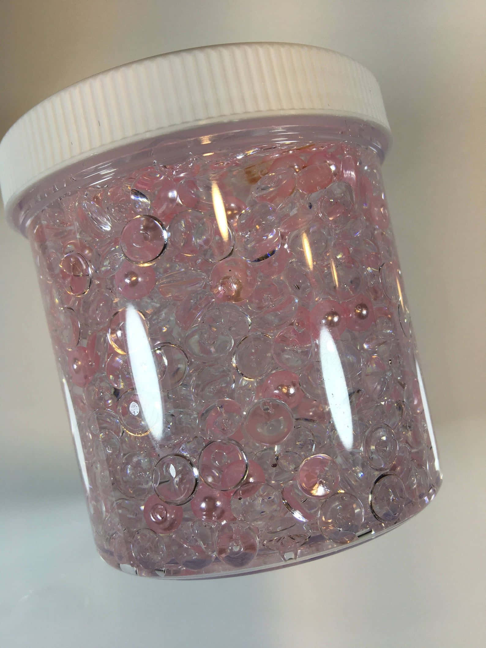 slime 桌布 壁紙 — 一個裝滿粉紅色和透明水珠的罐子，在明亮光線下柔和發光。