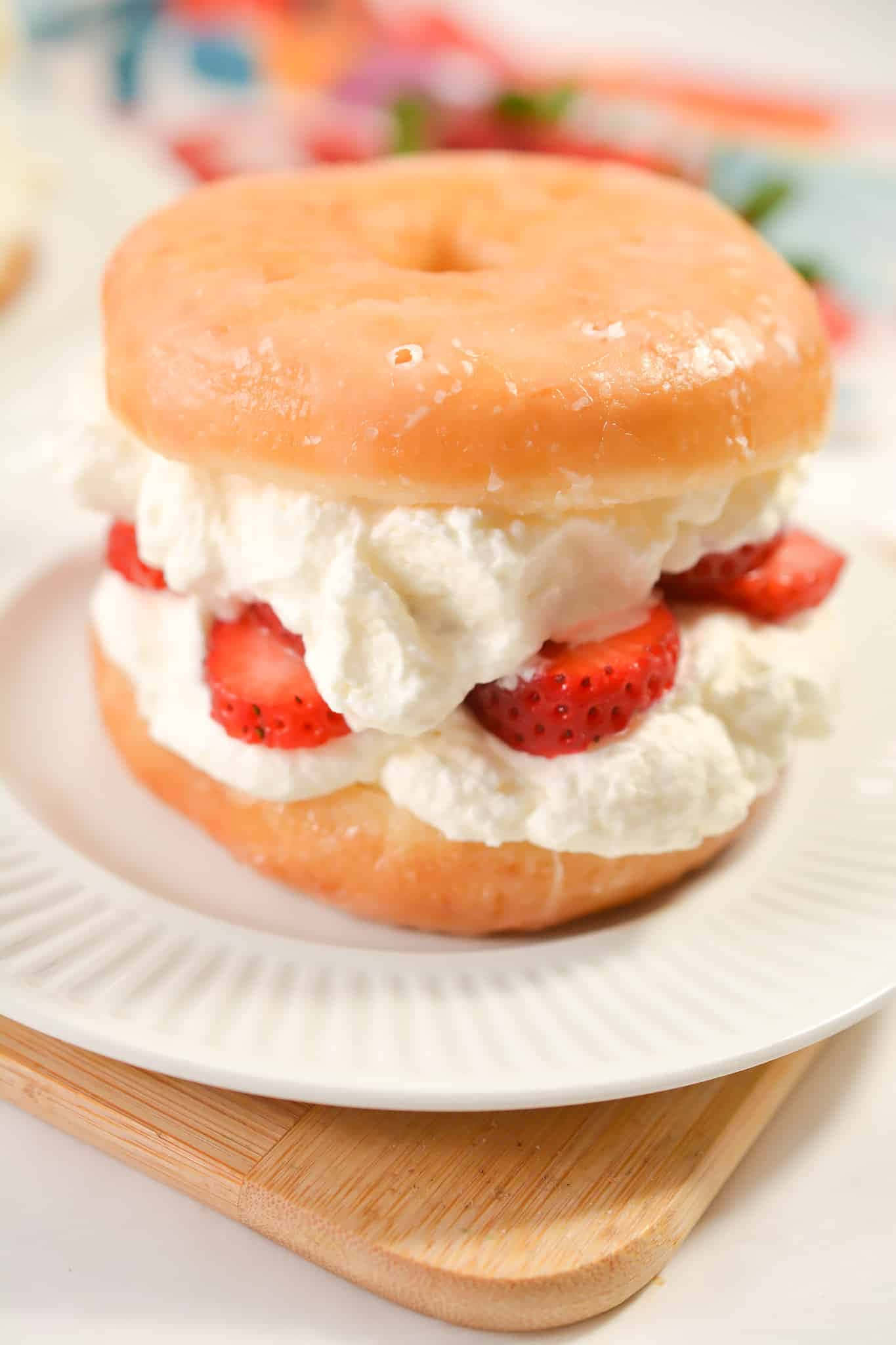 Glazed Donut 桌布 壁紙 — 一個裝滿鮮奶油和新鮮草莓的糖霜甜甜圈三明治放在木板上的白色盤子裡。