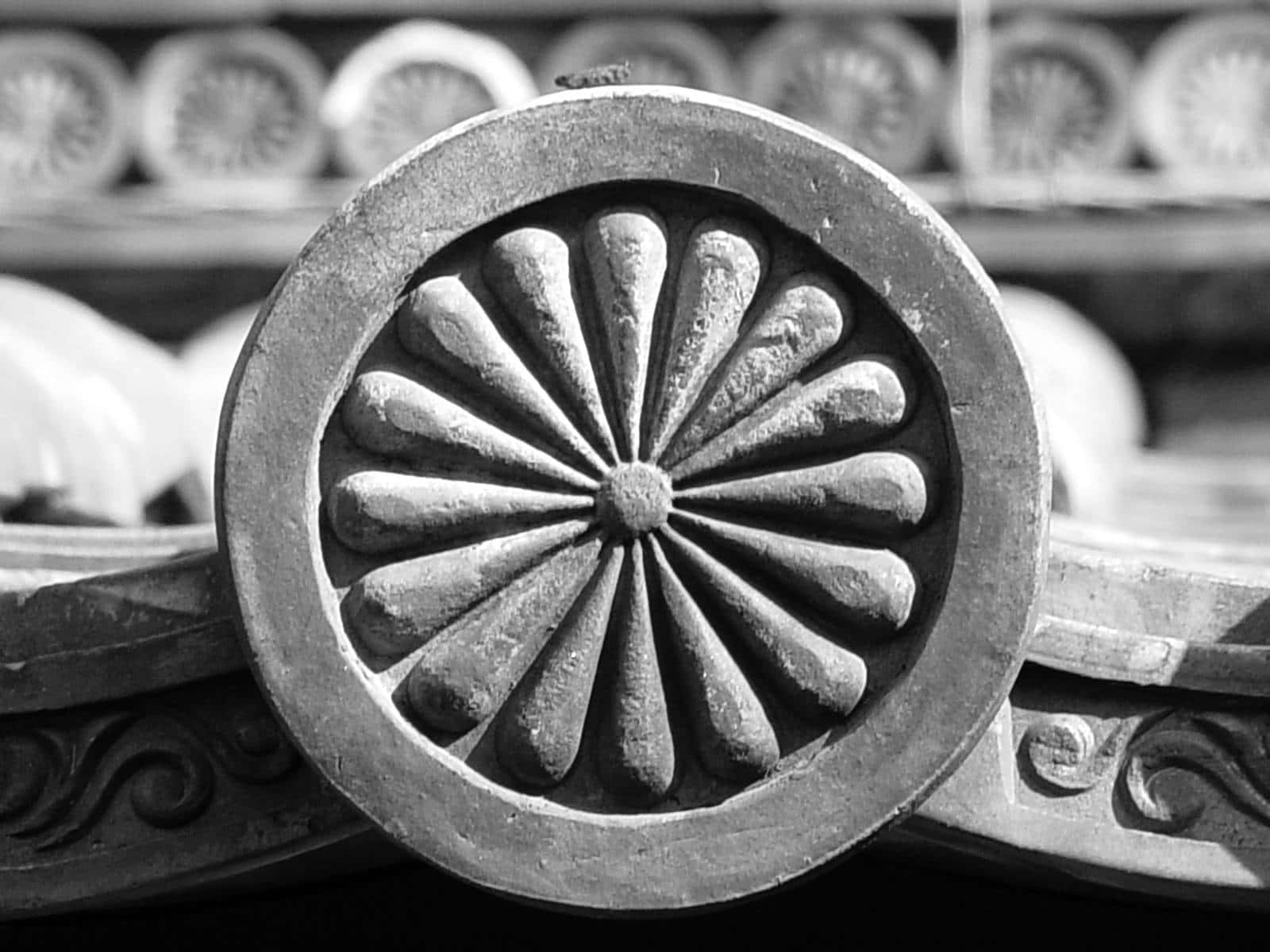 Ceramics 桌布 壁紙 — 一個裝飾性建築結構上帶有放射狀花瓣圖案的詳細圓形雕刻瓷磚的特寫黑白照片。