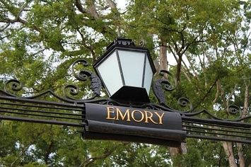  壁紙 — 一個裝飾性的黑色金屬標牌，上面有金色字母 'EMORY' 和一個復古燈籠，周圍環繞著茂密的綠樹。