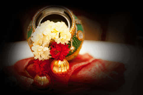 Hinduism 桌布 壁紙 — 一個裝飾性黃銅盆，帶有綠色琺瑯和金邊，在戲劇性的聚光燈下，將白色和紅色的花朵放在紅色布料上。
