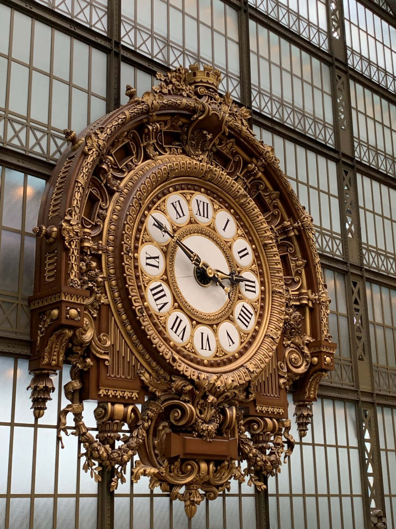 Clocks 桌布 壁紙 — 一個裝飾華麗的羅馬數字金色時鐘掛在大玻璃和金屬窗的背景上。