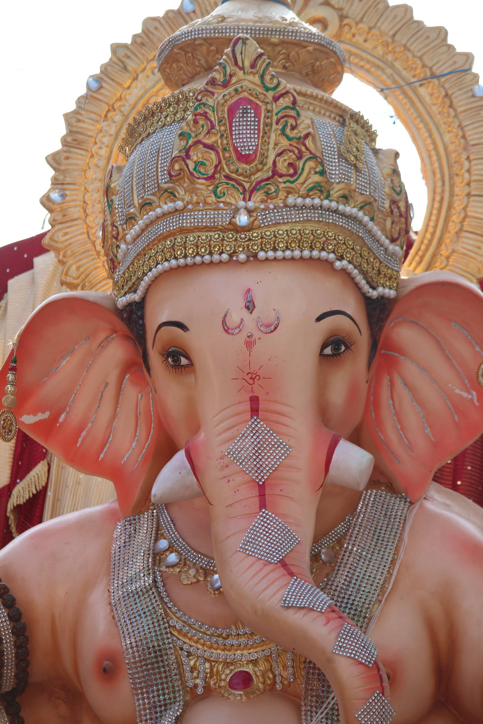Ganesh 桌布 壁紙 — 一個裝飾華麗的象神雕像特寫，飾有閃閃發光的珠寶和精緻的金色皇冠。