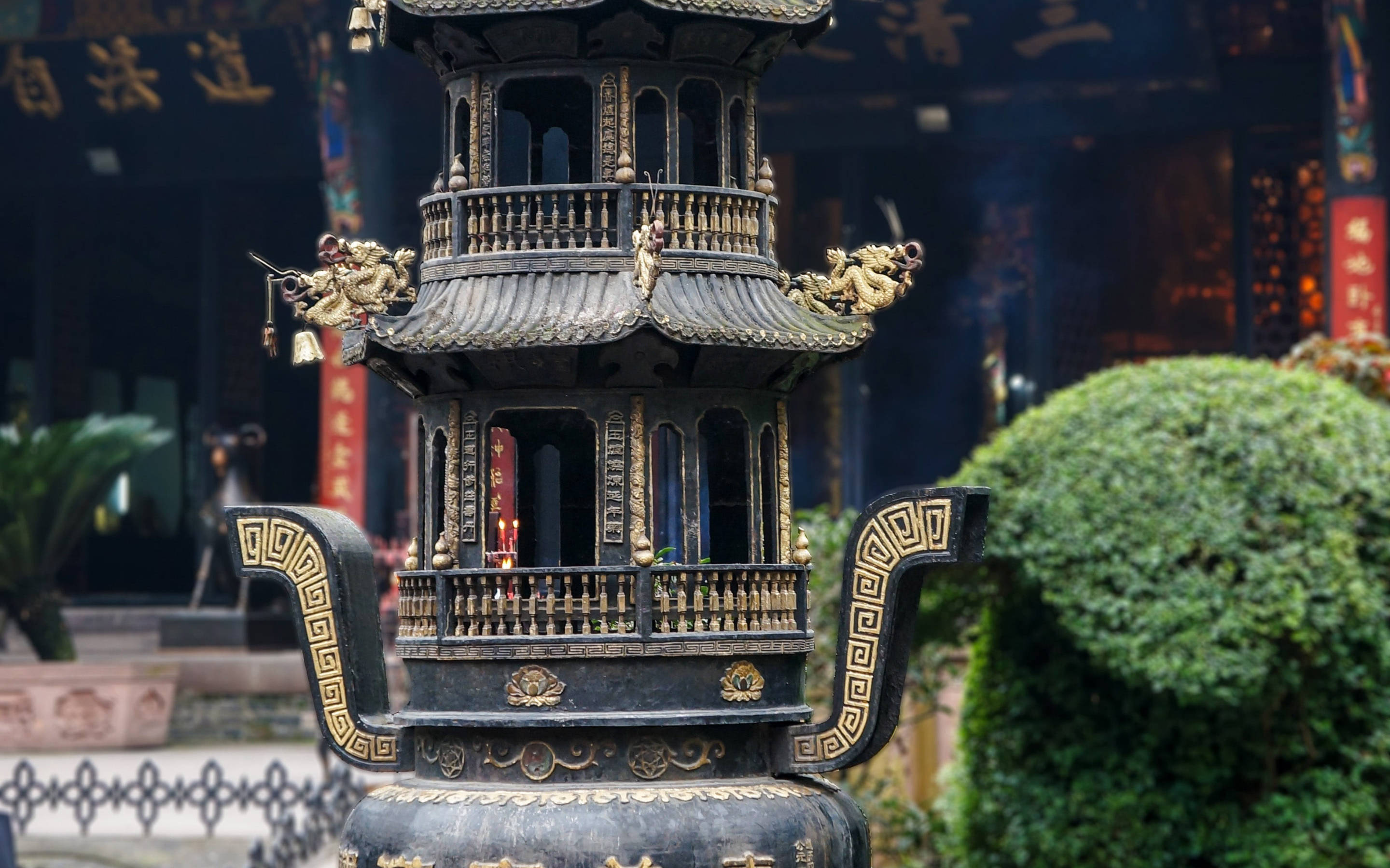 Chengdu 桌布 壁紙 — 一個裝飾華麗的黑色香爐，帶有金色龍紋和精緻雕刻，放置在傳統中國寺廟入口前。