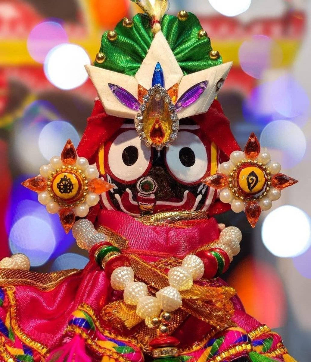 Jagannath 桌布 壁紙 — 一個裝飾鮮豔的傳統印度神像，飾有珠寶、珍珠和彩色布料，背景為散景效果。