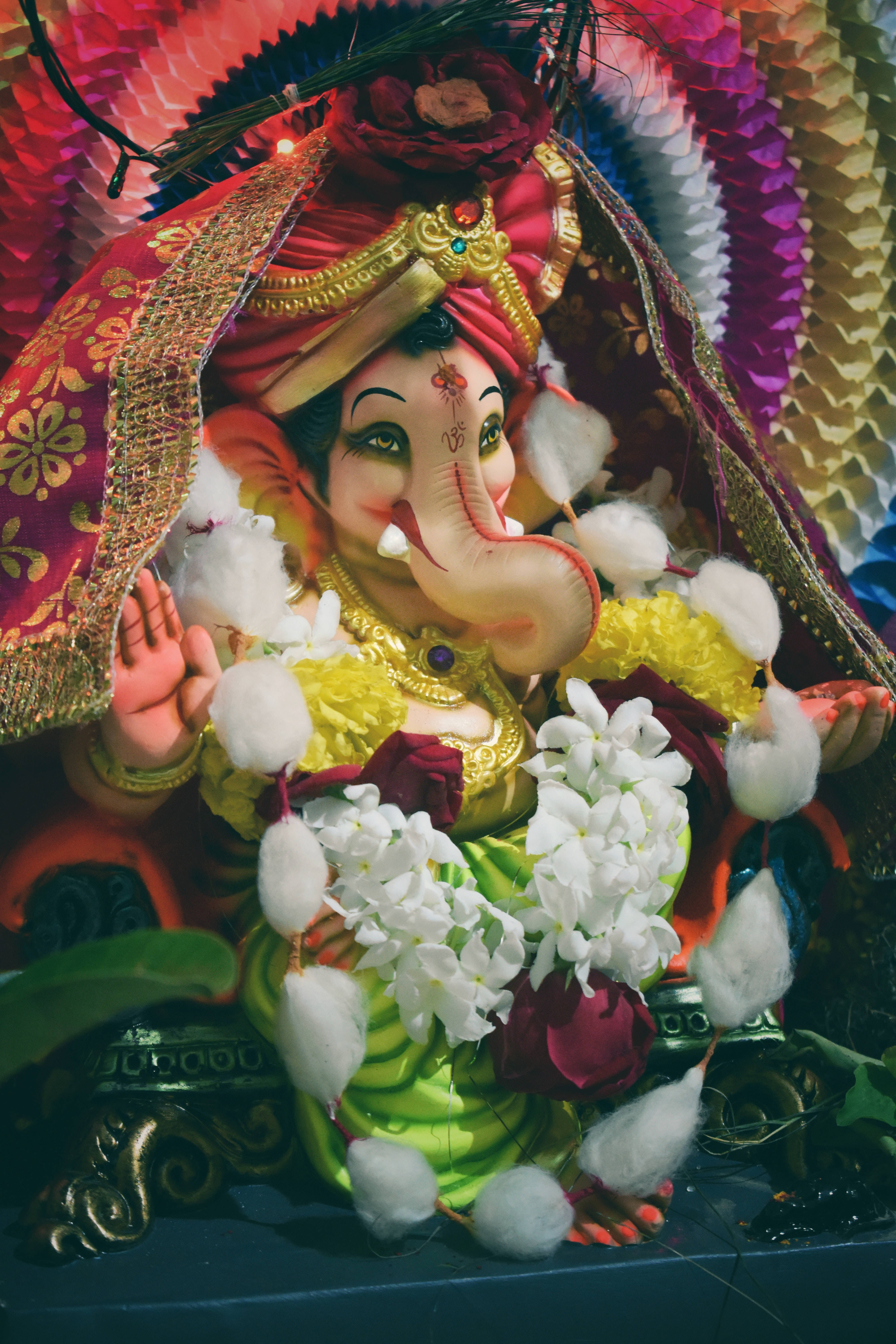 Ganesh 桌布 壁紙 — 一個裝飾鮮豔的象神像，飾有鮮花和色彩繽紛的布料，散發著節日的虔誠。