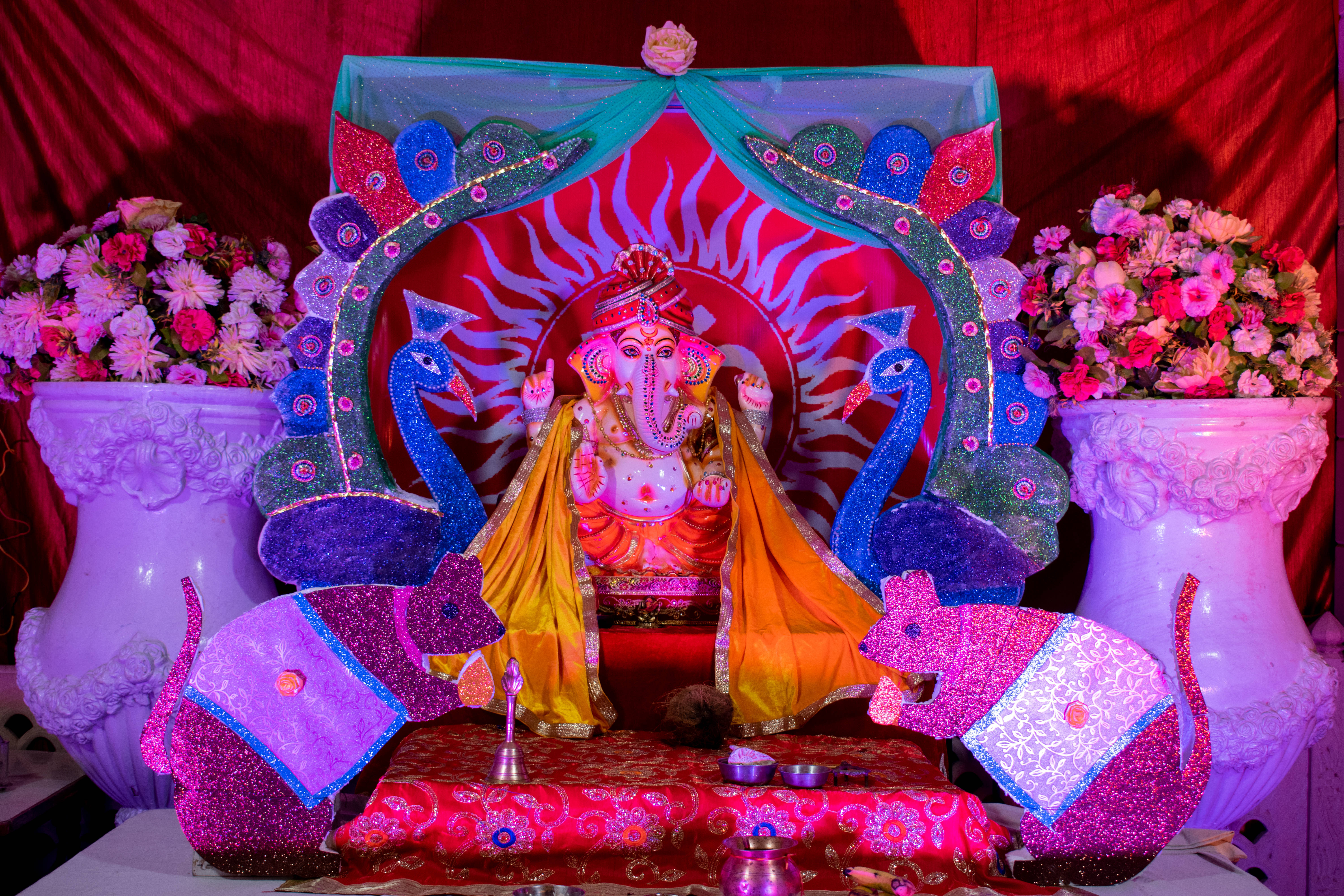 Bappa 桌布 壁紙 — 一個裝飾鮮豔的象神神像坐在兩隻孔雀和閃閃發光的大象之間，在紅色天篷下登基。