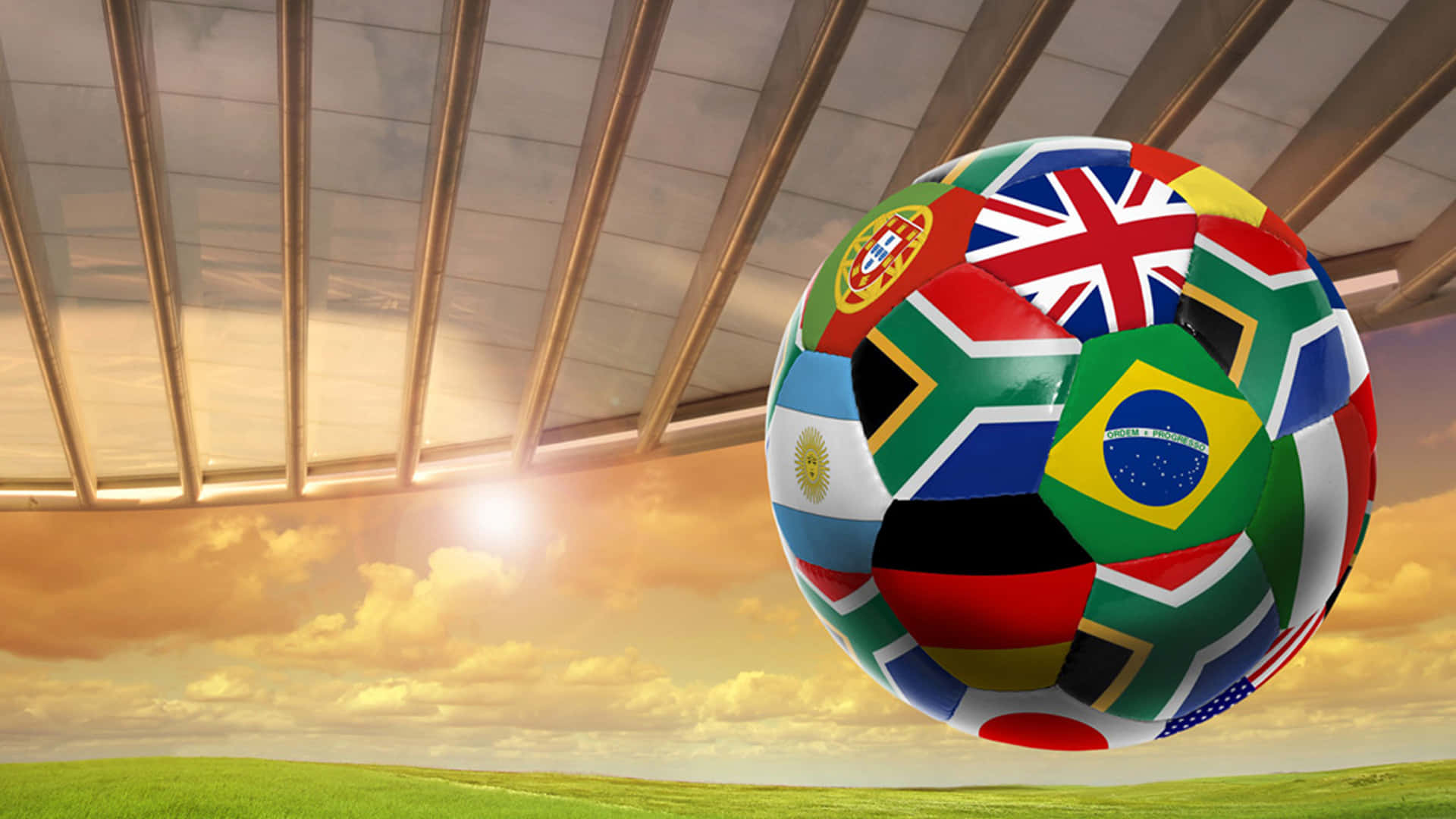 fifa 桌布 壁紙 — 一個覆蓋著各國國旗的足球，在金色夕陽下飄浮在體育館屋頂下的草地上。