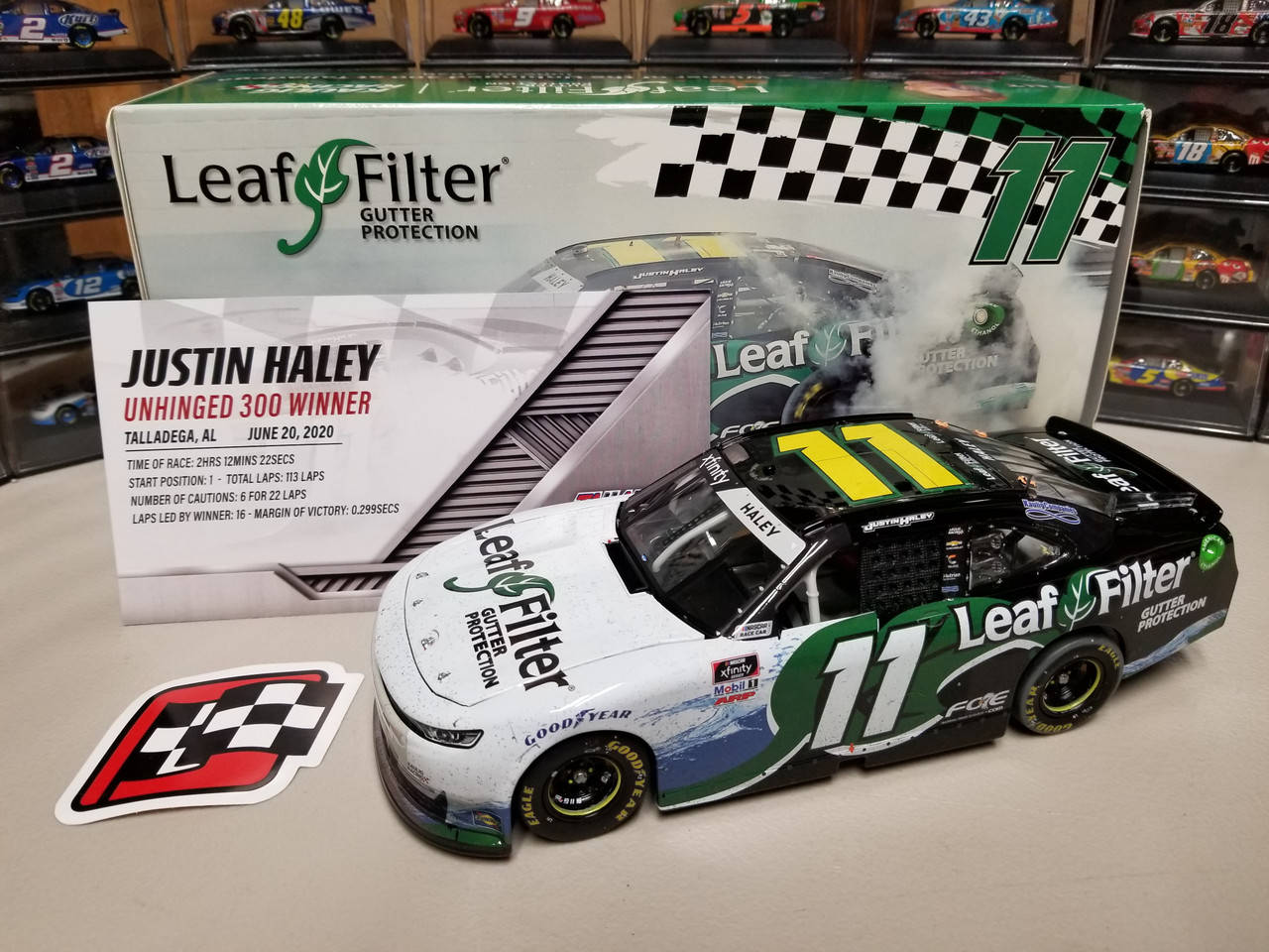 汽車 桌布 壁紙 — 一個詳細的11 Leaf Filter NASCAR賽車模型放在架子上，旁邊是它的盒子和格子旗貼紙。