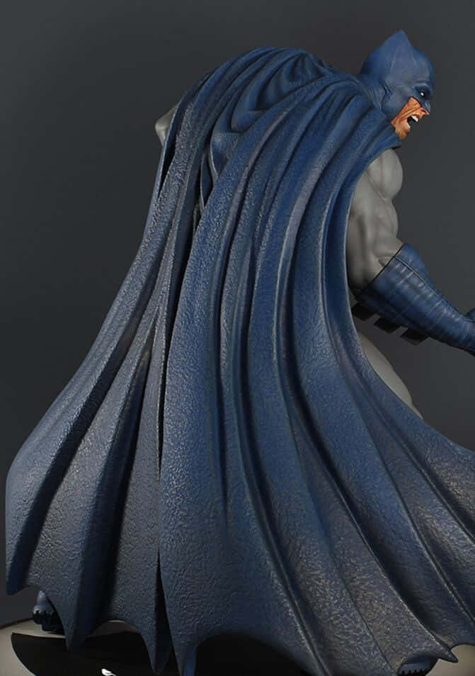 Batman The Dark Knight Returns 桌布 壁紙 — 一個詳細的3D渲染蝙蝠俠雕像，帶有飄逸的藍色斗篷和兇猛的表情，背景為深灰色。