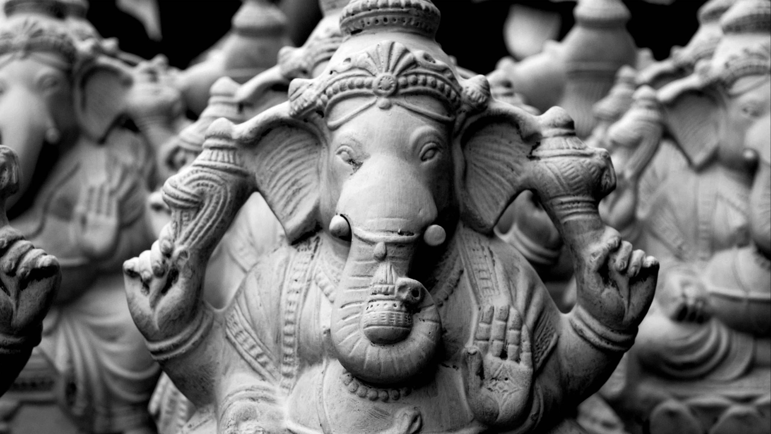 Ganesh 桌布 壁紙 — 一個詳細的Ganesha雕像的單色特寫，周圍是一排模糊的相似雕像。