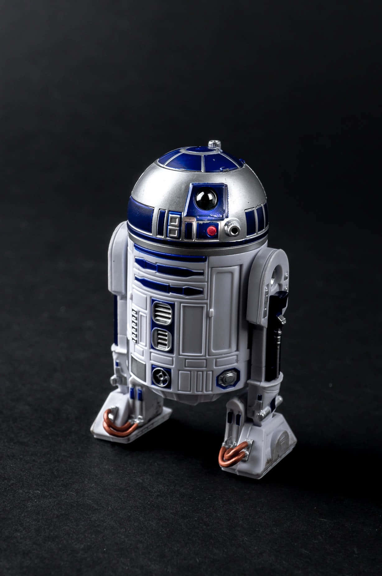 r2d2 桌布 壁紙 — 一個詳細的R2-D2機器人模型，在深色背景前帶有金屬銀色和藍色點綴。