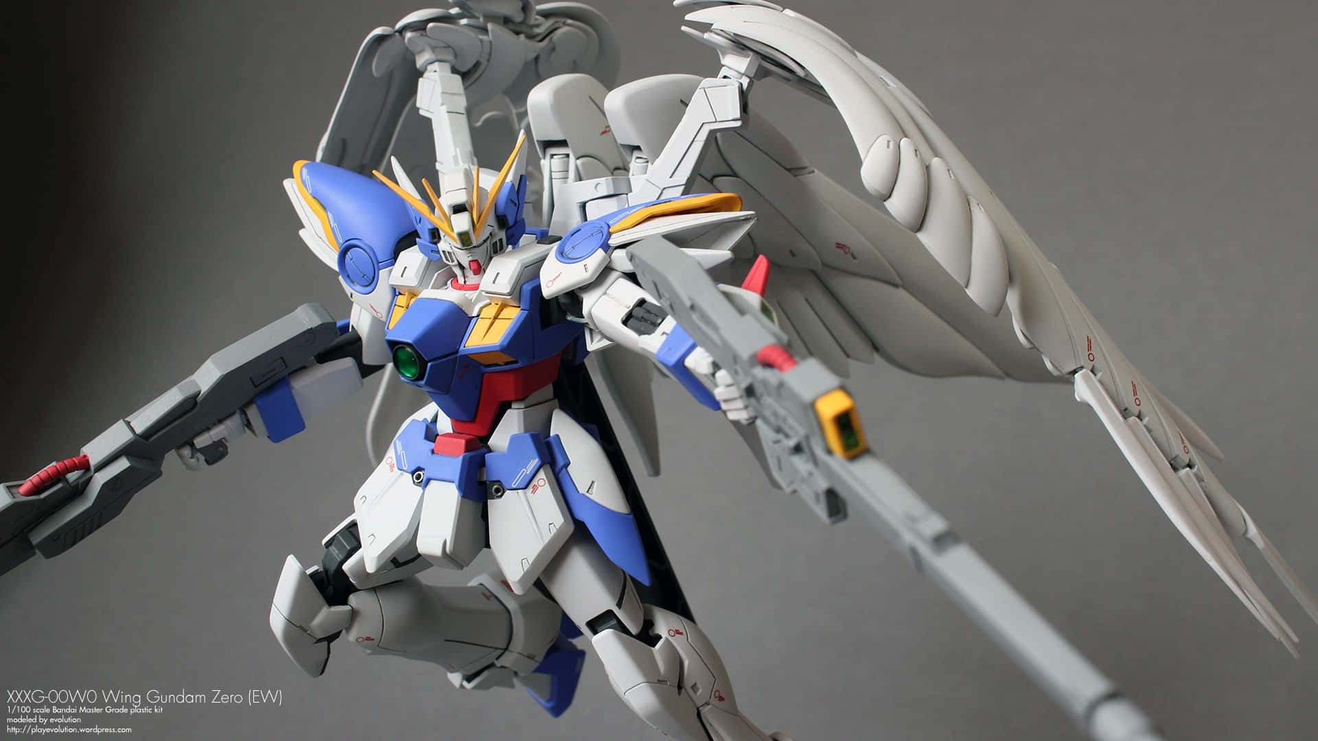 桌布 壁紙 — 一個詳細的Wing Gundam Zero EW模型，在灰色中性背景上動態擺出翅膀展開的姿勢。
