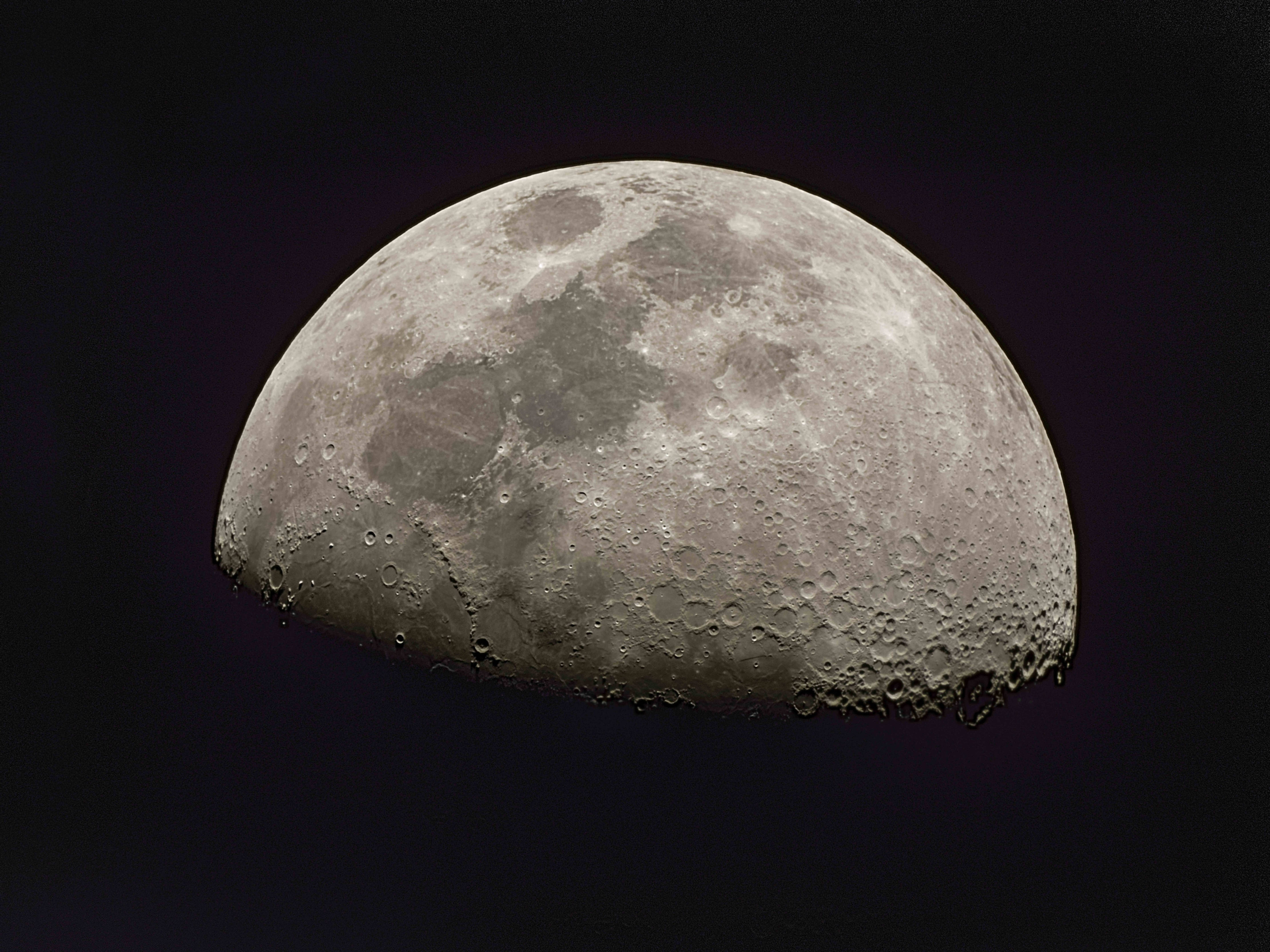 4K 太空 桌布 壁紙 — 一個詳細的半月亮，帶有隕石坑和月海，在深紫黑色的天空中柔和發光。