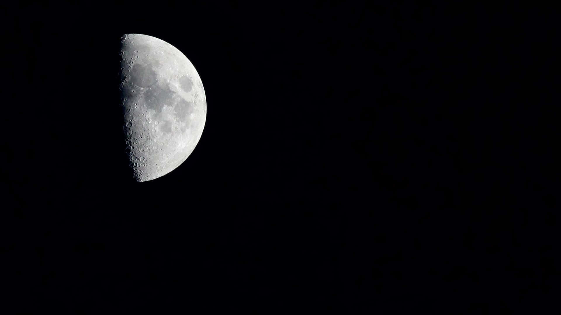 Half Moon 桌布 壁紙 — 一個詳細的半月亮在深邃的黑色夜空中發光，可見隕石坑和陰影。