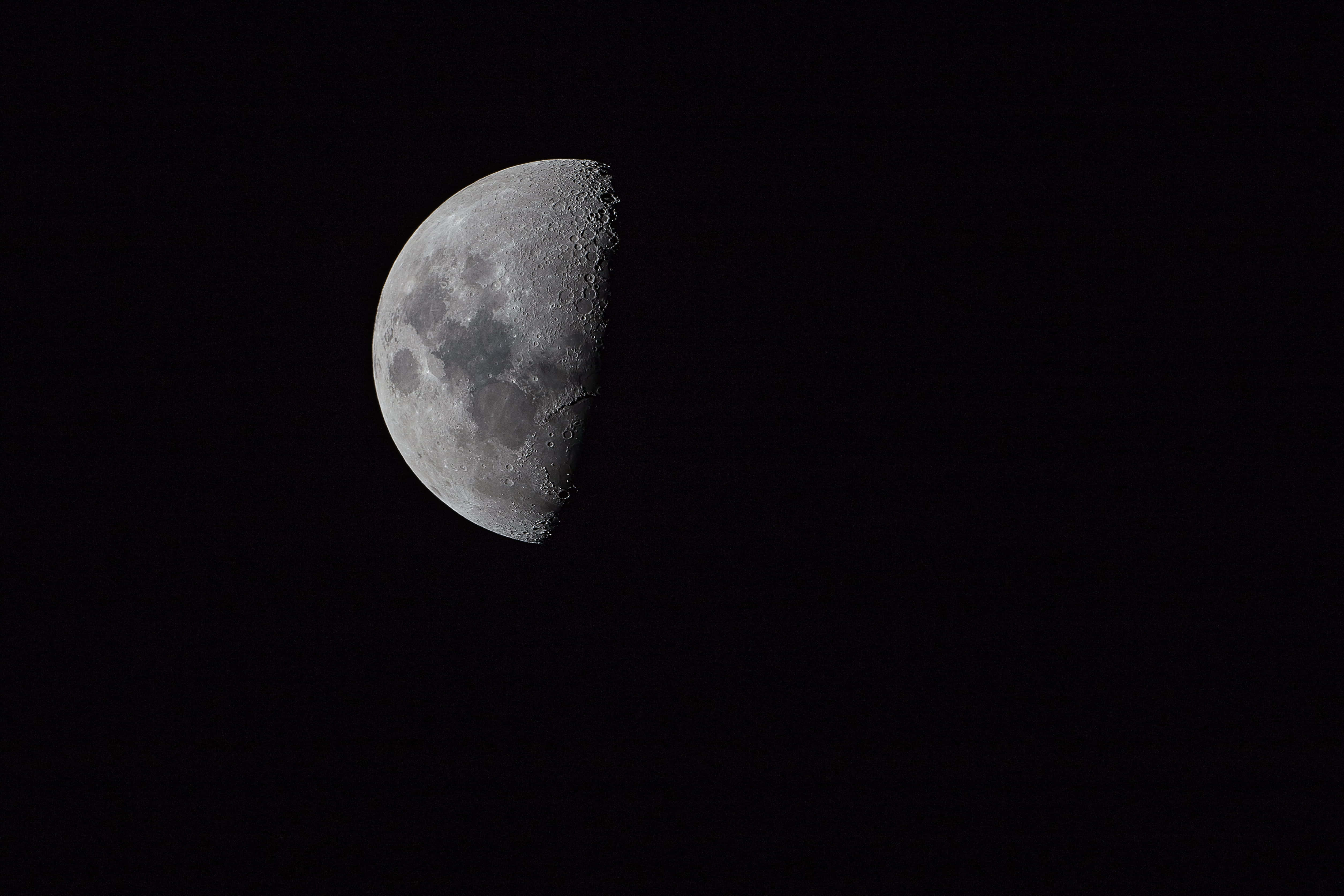 Half Moon 桌布 壁紙 — 一個詳細的半月亮在深黑色的夜空中發光，顯露出隕石坑和月球地形。